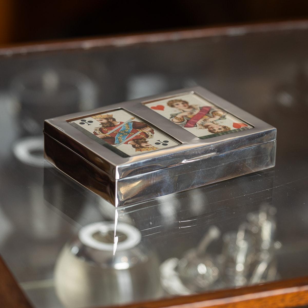 Un superbo portasigari o portacarte in argento massiccio britannico del XX secolo. La scatola ha una forma rettangolare con una finitura esterna lucida. Il coperchio è ornato da due inserti in vetro, ognuno dei quali mostra una carta da gioco come