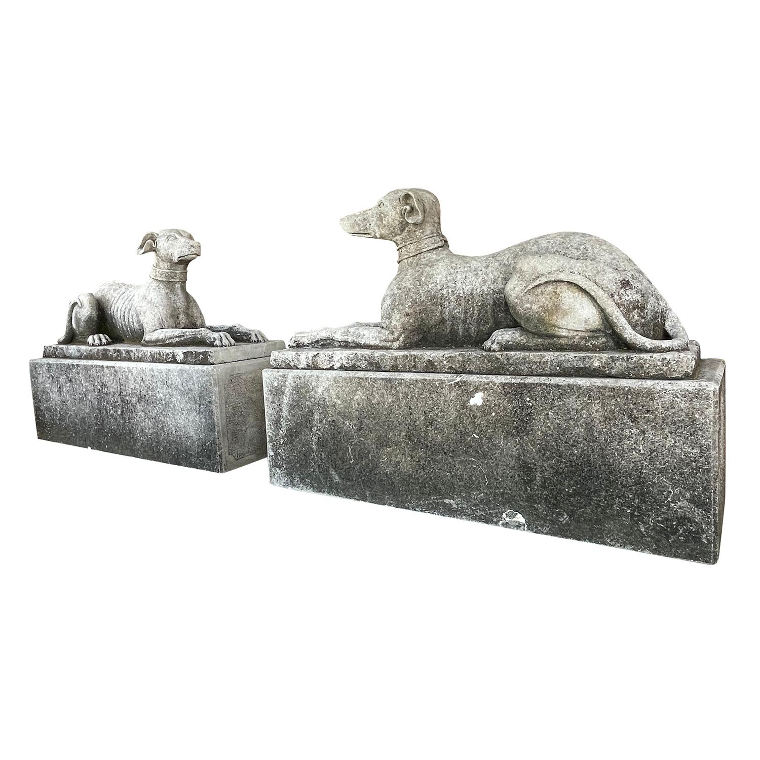 A pair of hand carved limestone English whippets or greyhounds like. The antique garden statues have raised heads, and in an alert extended position. These vintage stone dogs have fine detailed carvings and are in good condition. They are positioned