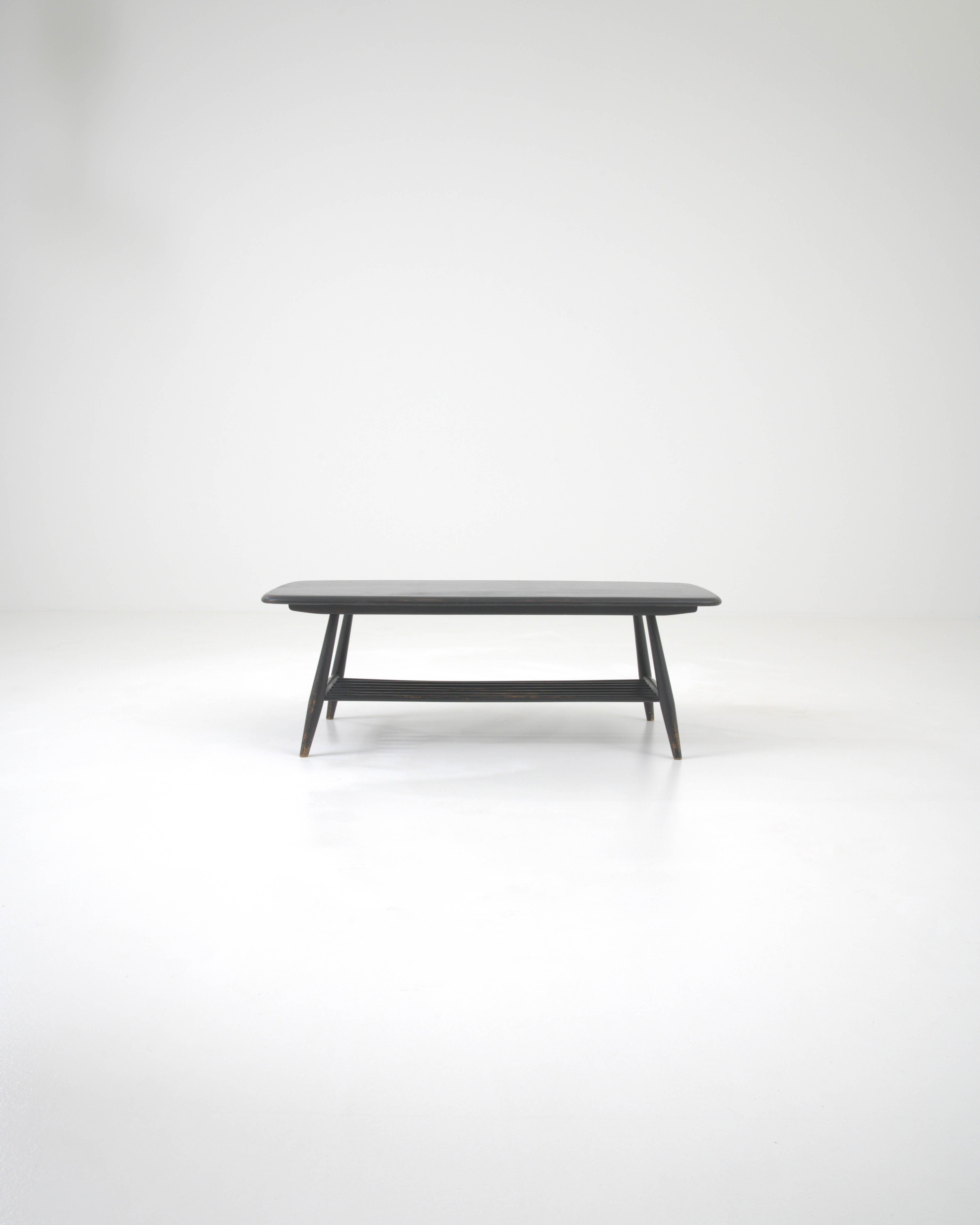Embrace the minimalist charm of this 20th Century British Wooden Patinated Coffee Table, a piece where simplicity and history converge. The table’s surface, enveloped in a dark patina, bears the subtle yet evocative marks of time, lending a sense of