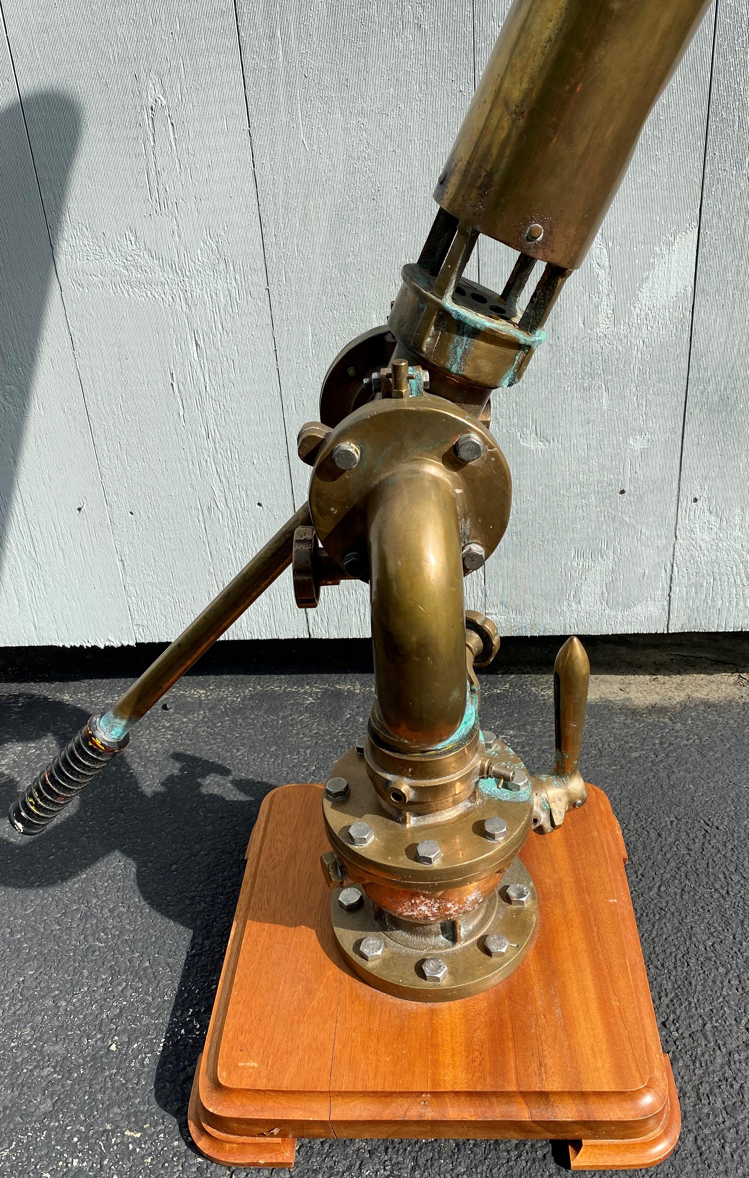 A fine example of a large bronze and copper marine fire monitor or adjustable water cannon used on a ship, mounted to a pivoting base with mounting coupling, displayed on a wooden plinth. These monitors or cannons were not only used to help fight
