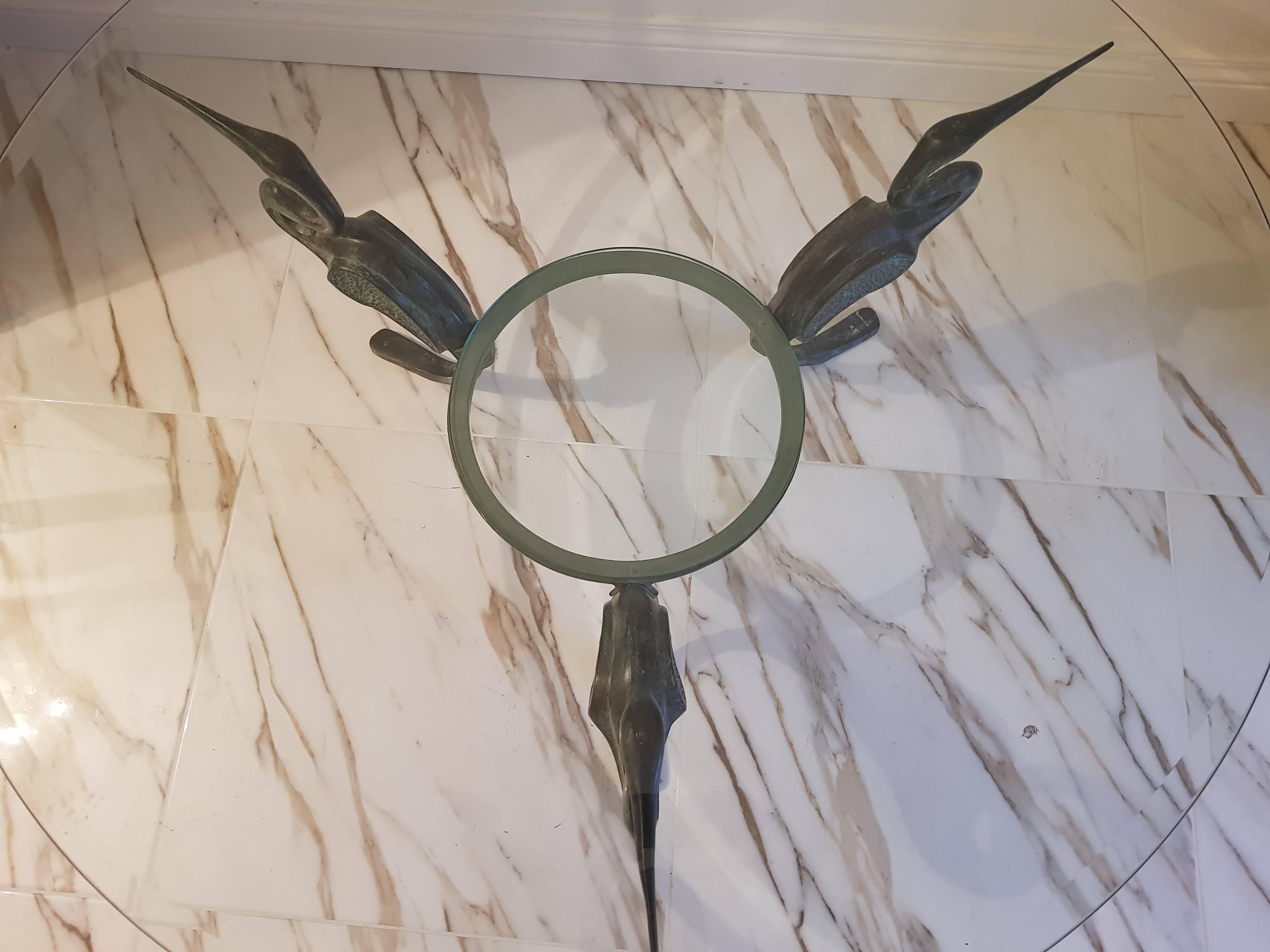 A very unique bronze heron table with three herons holding the glaze plate, what is very unique about this table is that the herons feet are merged to one and the wings are artisticly covered. the extra snale holds the glaze plate and it has a green
