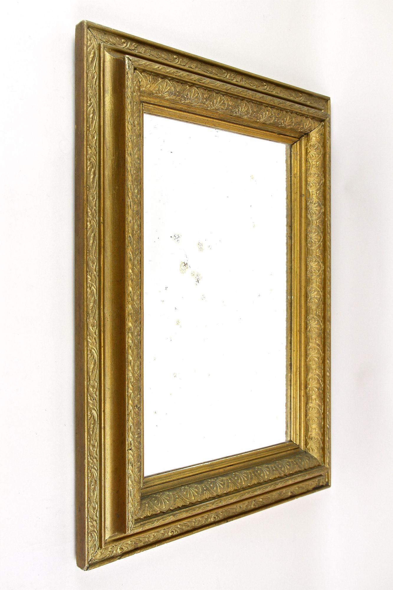 Charming bronzed/ gilt Art Nouveau wall mirror out of Austria from the period around 1900. This lovely early 20th century mirror impresses with an elaborately crafted broad gilt and bronzed frame work adorned by artfully floral design elements -