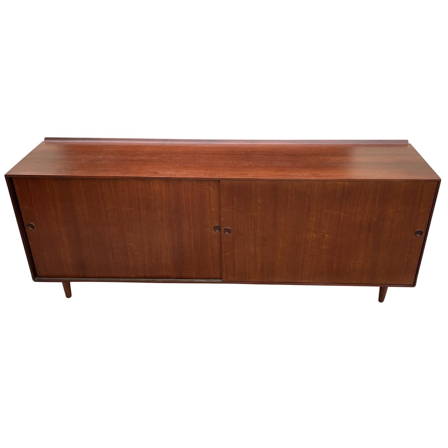 A vintage Mid-Century modern Danish, American cabinet made of hand crafted Walnut, designed by Finn Juhl and produced by Baker in good condition. The Scandinavian sideboard is composed with two sliding doors, standing on six small wooden feet. The