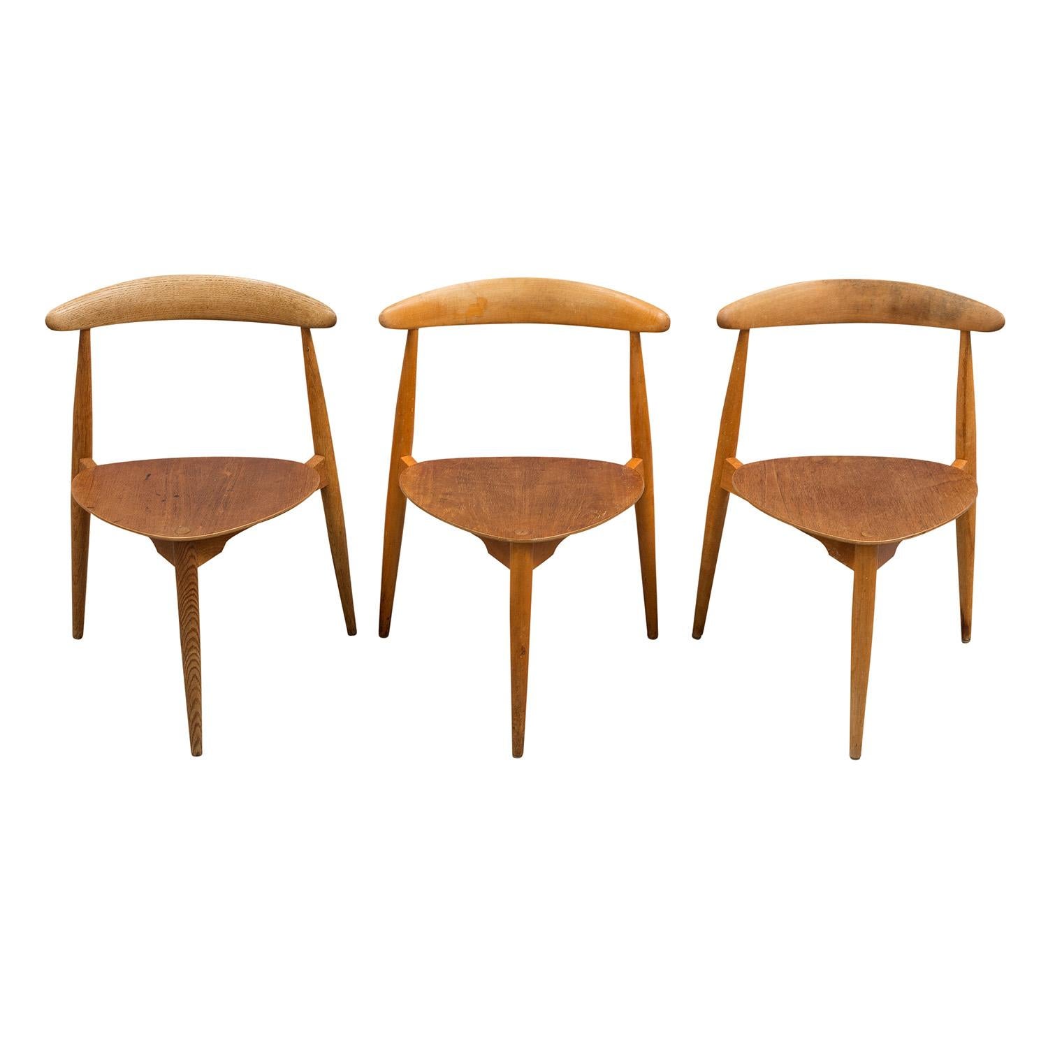 A vintage Mid-Century Modern Danish set of three side chairs made of hand crafted teakwood, designed by Hans J. Wegner and produced by Fritz Hansen with heart shaped seats, three sculpted legs and seat backs, in good condition. Model H 4013. Wear