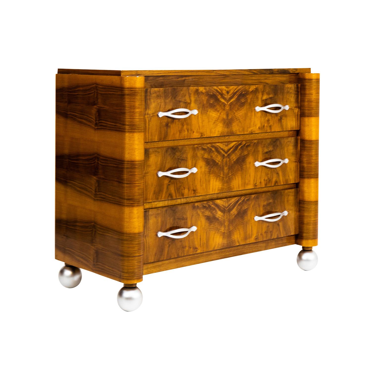 A dark-brown, vintage Art Deco commode made of hand crafted polished veneered Walnut with three large drawers, in good condition. The chest of drawers is standing on four round, silver ball feet with rounded corners and silver handles, pulls. Wear