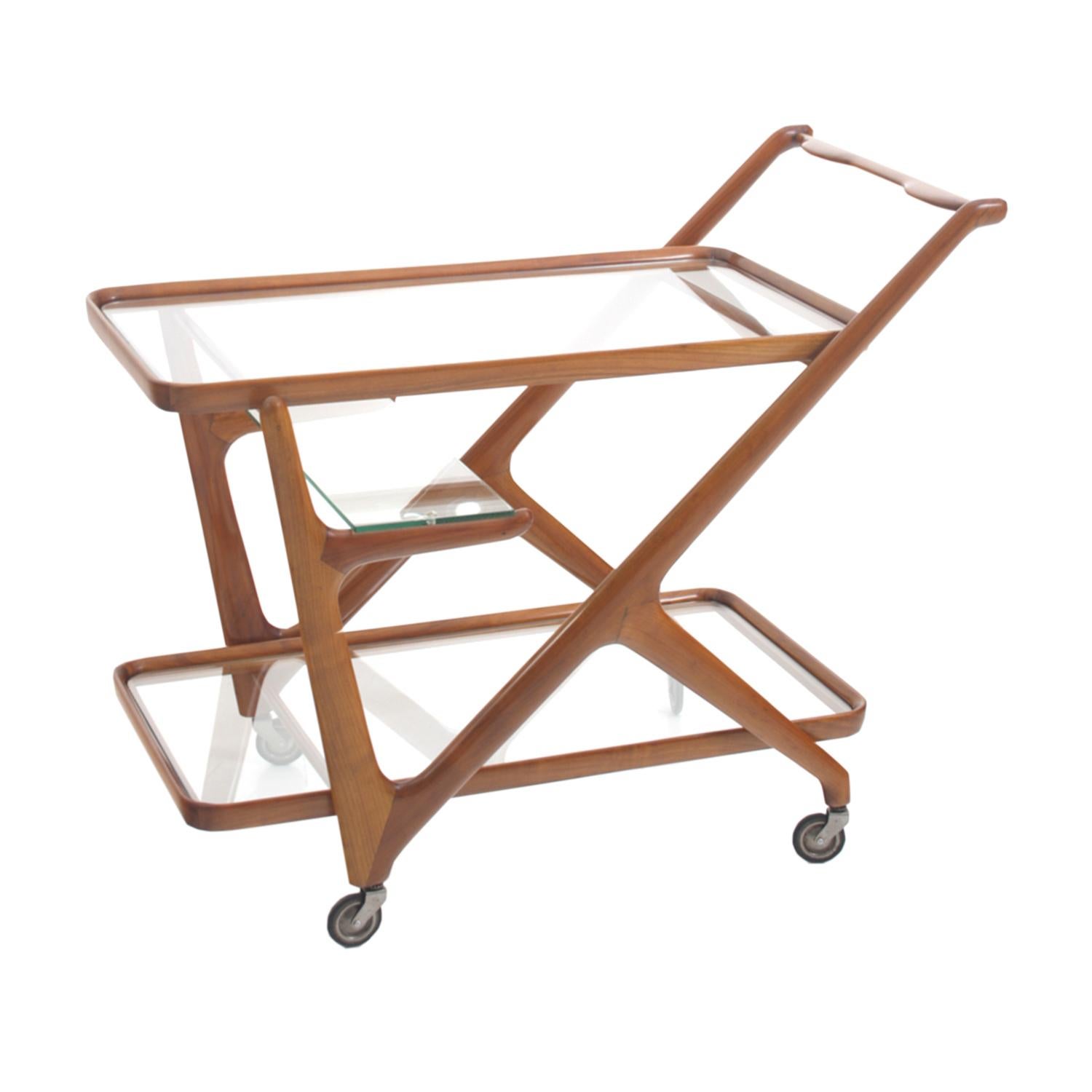 A light-brown, vintage Mid-Century modern Italian bar cart made of hand crafted polished Walnut, designed by Cesare Lacca and produced by Cassina, enhanced by detailed wood carvings, in good condition. The serving tea trolley is composed with two
