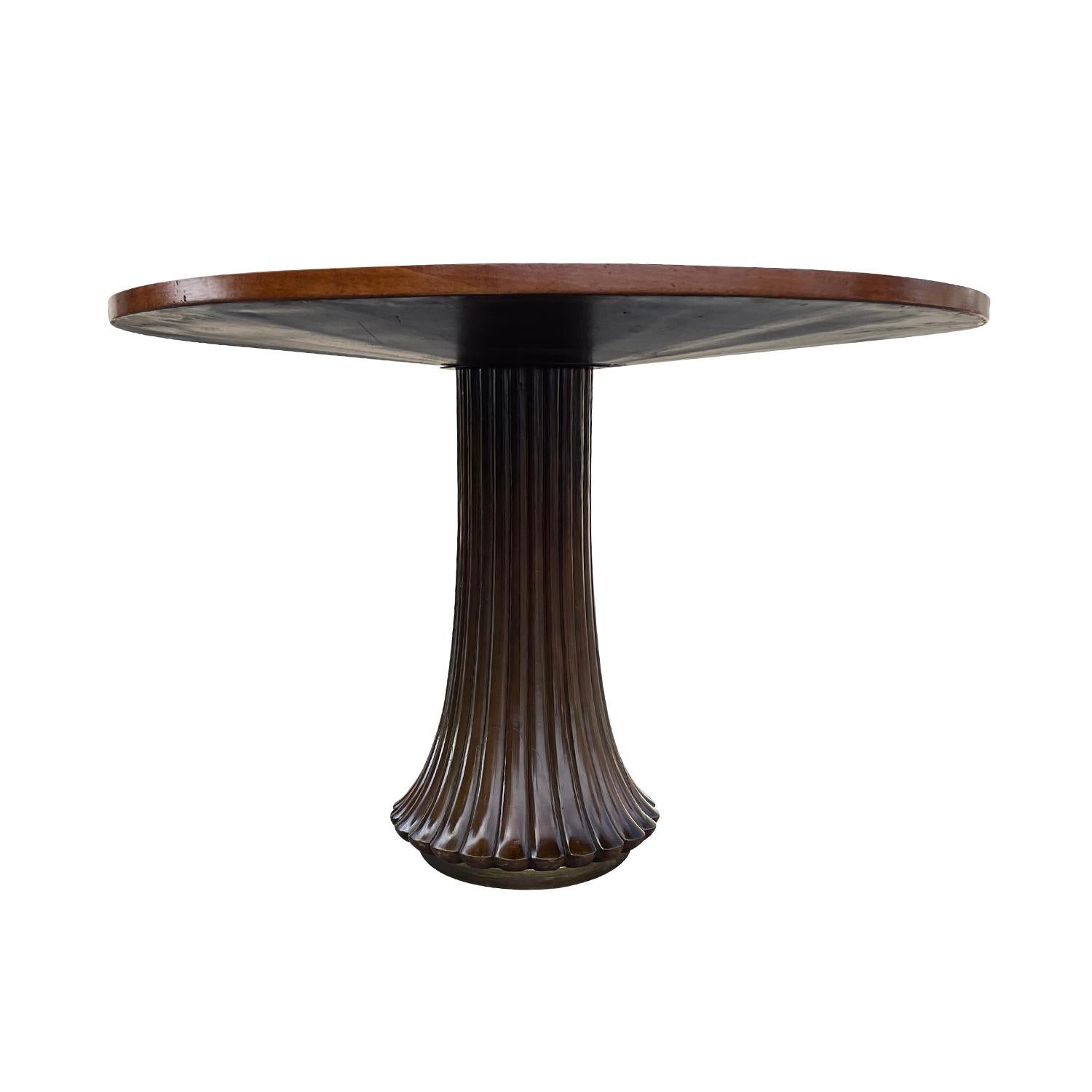 A vintage Mid-Century Modern dining room table made of hand crafted polished Rosewood with a round Walnut top, in good condition. The sculpture table is supported by a round wooden, brass foot enhanced by detailed wood carvings. Wear consistent with