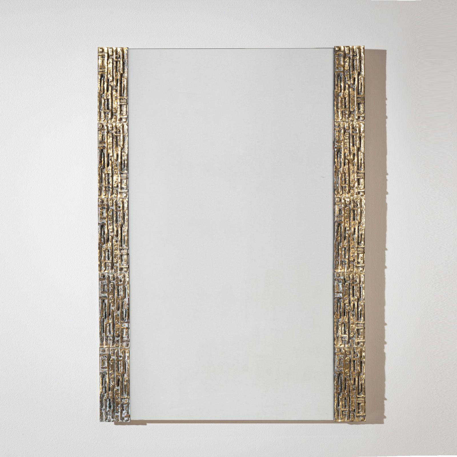 A rectangular wall mirror attributed to Luciano Frigerio in the 1970s. The decorative brass frame features a unique pattern of irregular elevations and depressions, creating a cohesive and bold Brutalist aesthetic that epitomizes the era's design