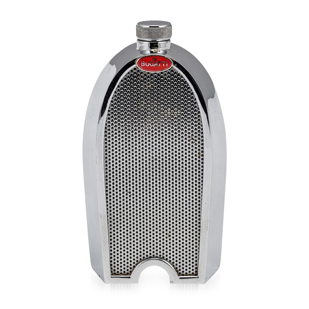 A vintage Bugatti chrome radiator grille decanter made in England in the 1970s, bearing the red enamel radiator badge. The decanter is equipped with a “slot” in the casing at the rear allowing visibility of the contents with baize cloth to the base.