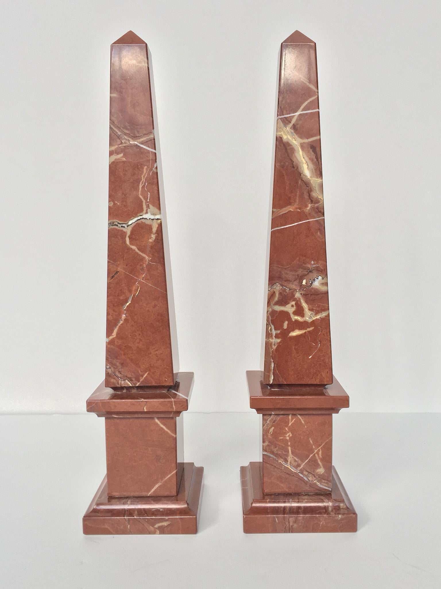 A notable pair of solid marble obelisks in a burnt umber hue. The marble is beautifully veined with swirls of taupes and grays. The base underside is lined with a protective felt cover. Statuesque even in their small size, these decorative obelisks