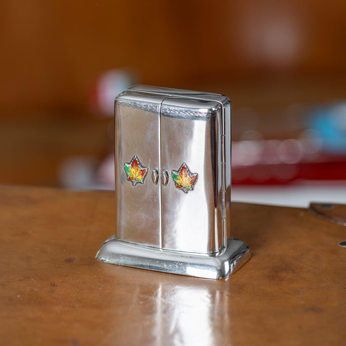 Antique early-20th Century Canadian solid silver playing cards case. This box features a smooth outer case, flared base which holds a cabinet-shaped box adorned with colourful enamel maple leaves. Upon opening the case, a deck of playing cards are
