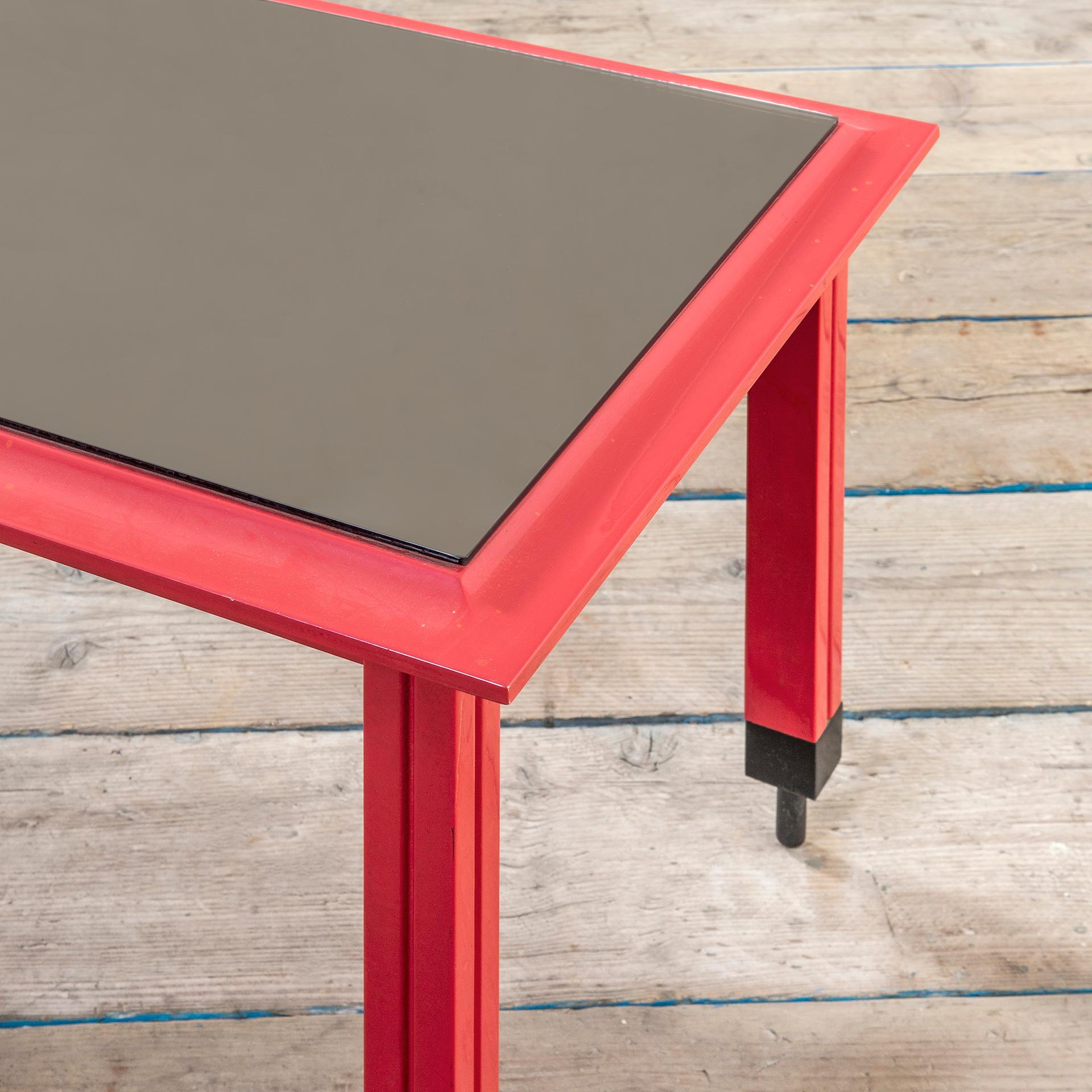 Table basse conçue par Carlo De Carli dans les années 60 pour Sormani Production. La structure est en bois laqué rouge, le plateau est recouvert d'un verre miroir ; le détail le plus singulier se trouve sur les pieds de cette table, en effet chaque