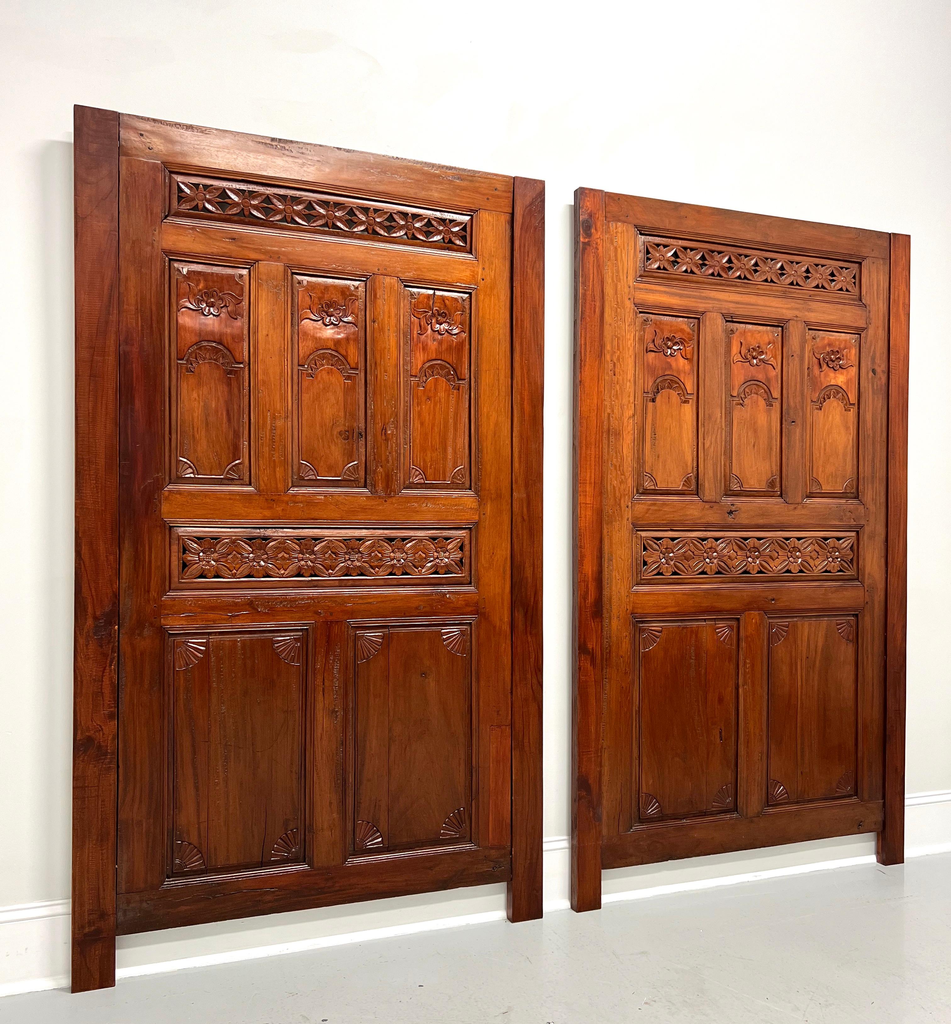 A pair of Asian style Balinese carved doors converted for use as headboards, unbranded. Solid mahogany doors with hand carved details, mounted to matching mahogany side pieces to raise up, and an unfinished back with a removable wall mounting brace.