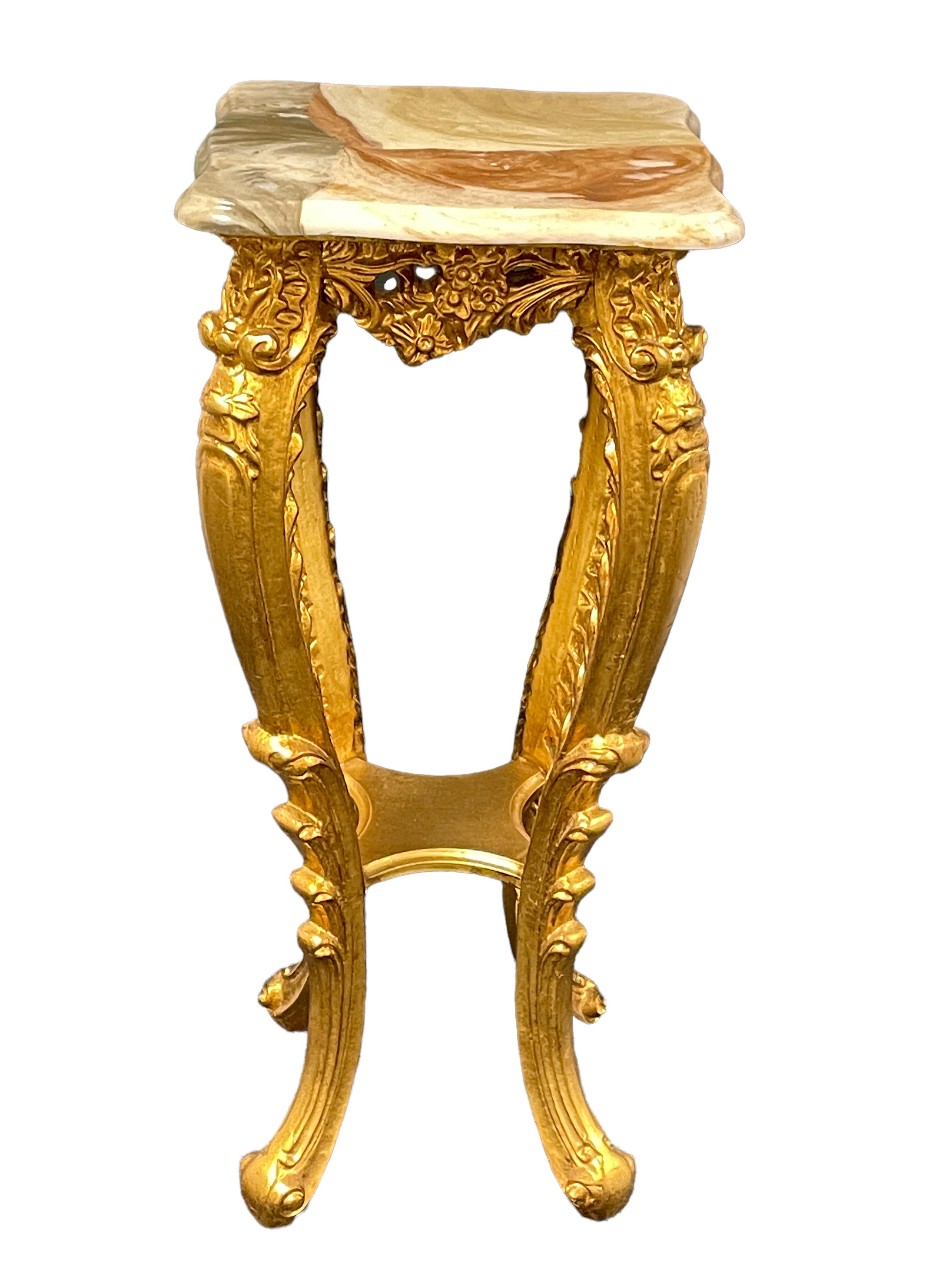 A good quality 20th century gilt wood, marble topped console table pedestal in the Hollywood Regency style. It has carved wood and plaster work decoration to the legs and around the rim at the wood under the marble plates. Feet are made in the style