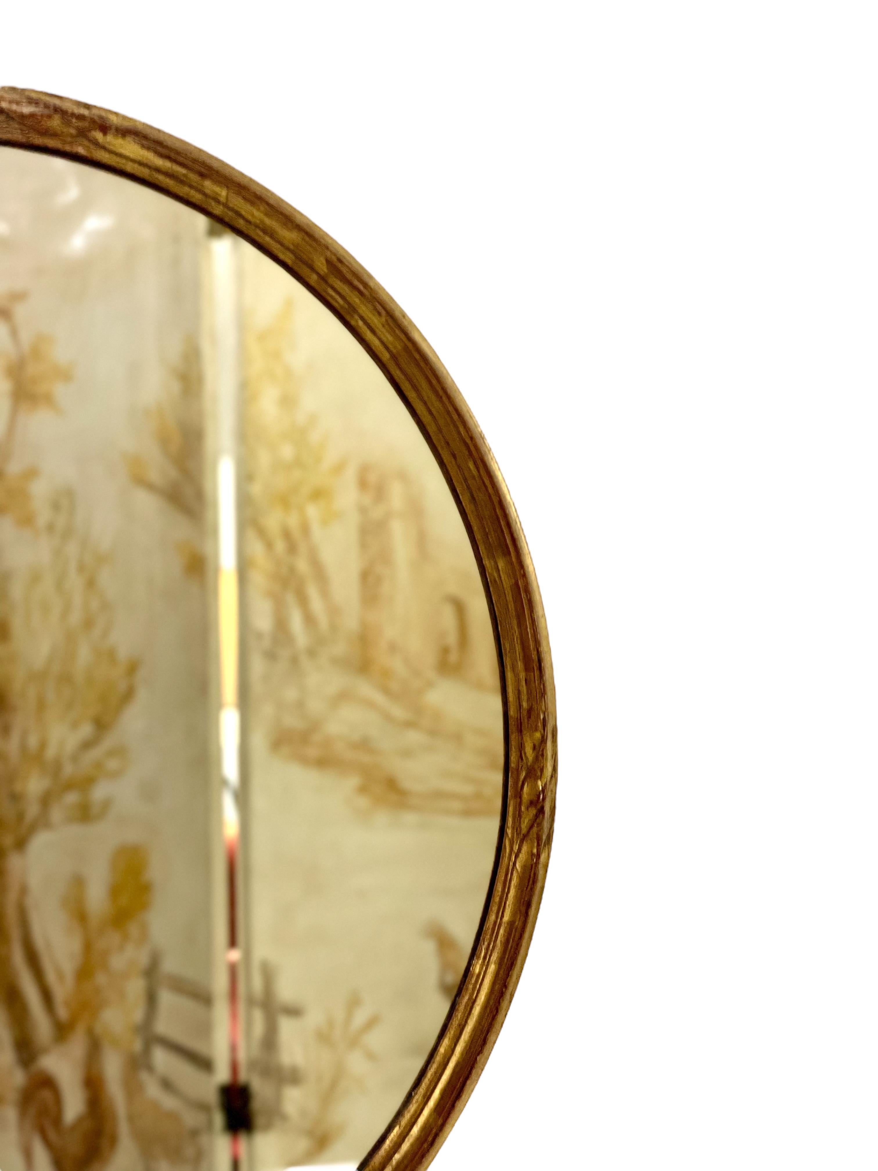 A pretty little oval wall mirror in a simple, but elegant giltwood frame embellished with carved elements of decoration on its four opposing sides. Dating from the 20th century, this mirror can be hung either landscape or portrait, and is in