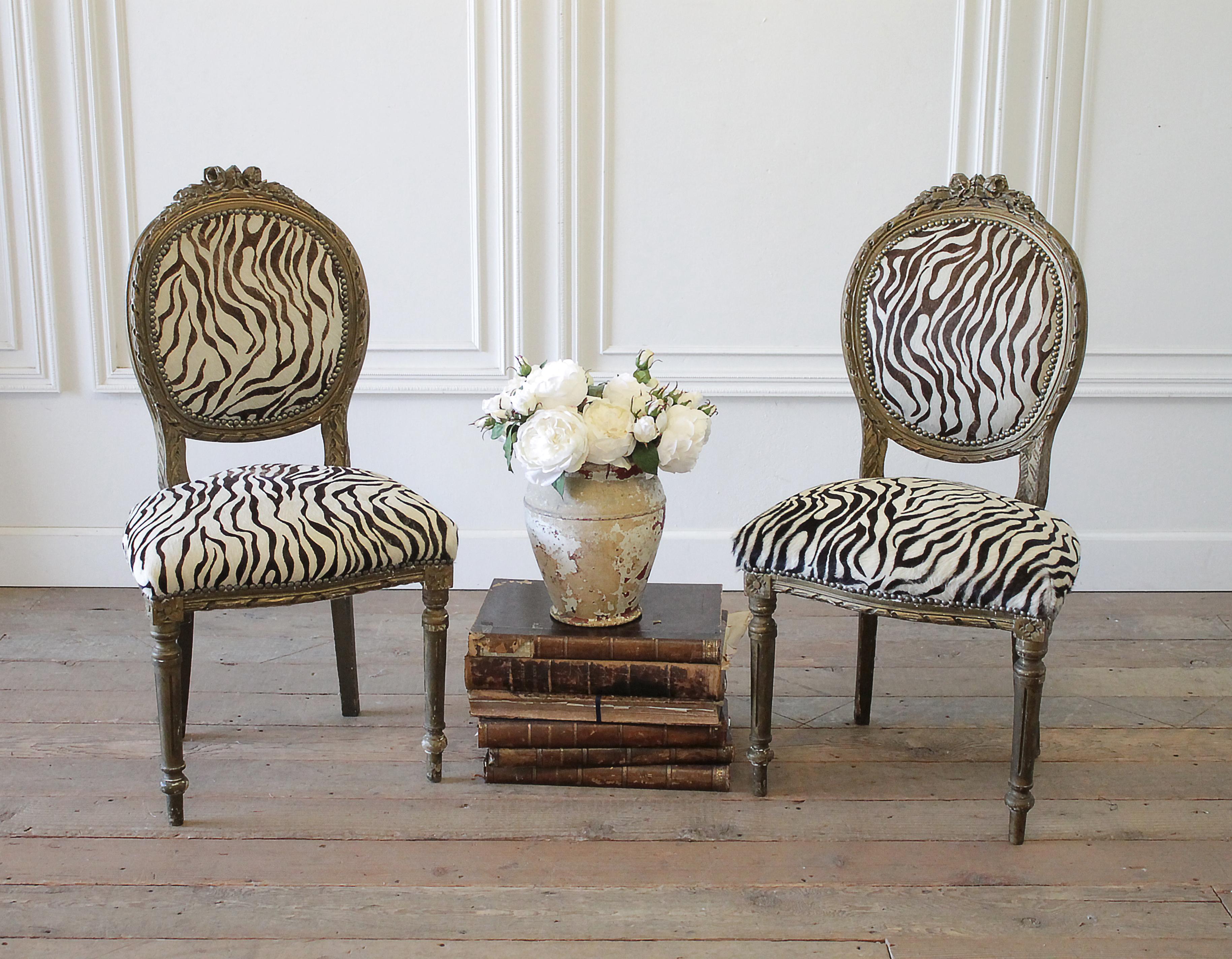 20th century carved giltwood zebra upholstered Louis XVI style chairs
Gilt finish has an aged patina, with chipping exposing a white finish underneath. Legs are solid and sturdy. Upholstery is done in a zebra style printed hair on hide, with