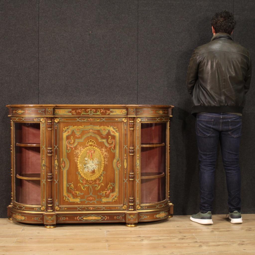 French sideboard from the 20th century. Furniture in carved, lacquered, gilded and hand painted wood with very pleasant floral decorations. Sideboard with three doors, the central one finely painted with a basket of flowers on a golden background