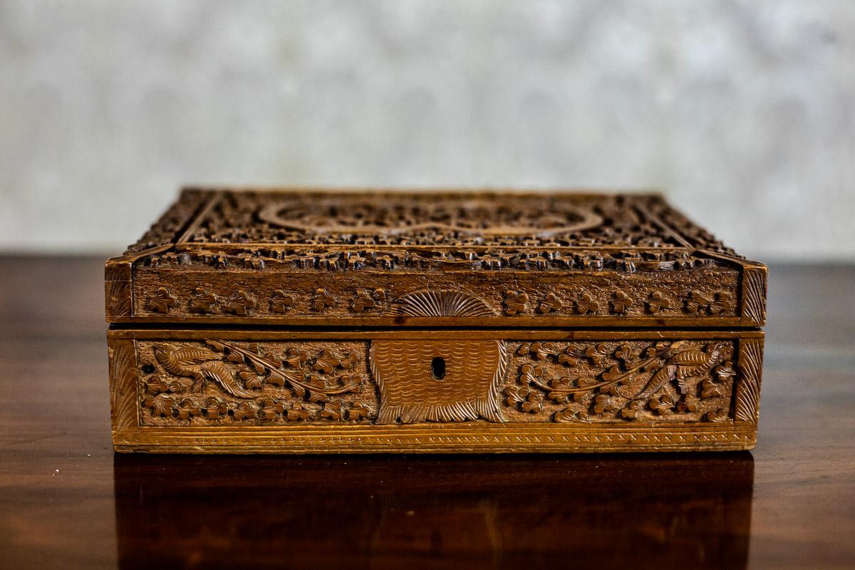We present you a small wooden coffret, covered with floral relief decoration.
There are compartments at its bottom.
Similarly to the lid, they are lined with plush.

This item is in very good condition. The key is missing. Moreover, the plush is
