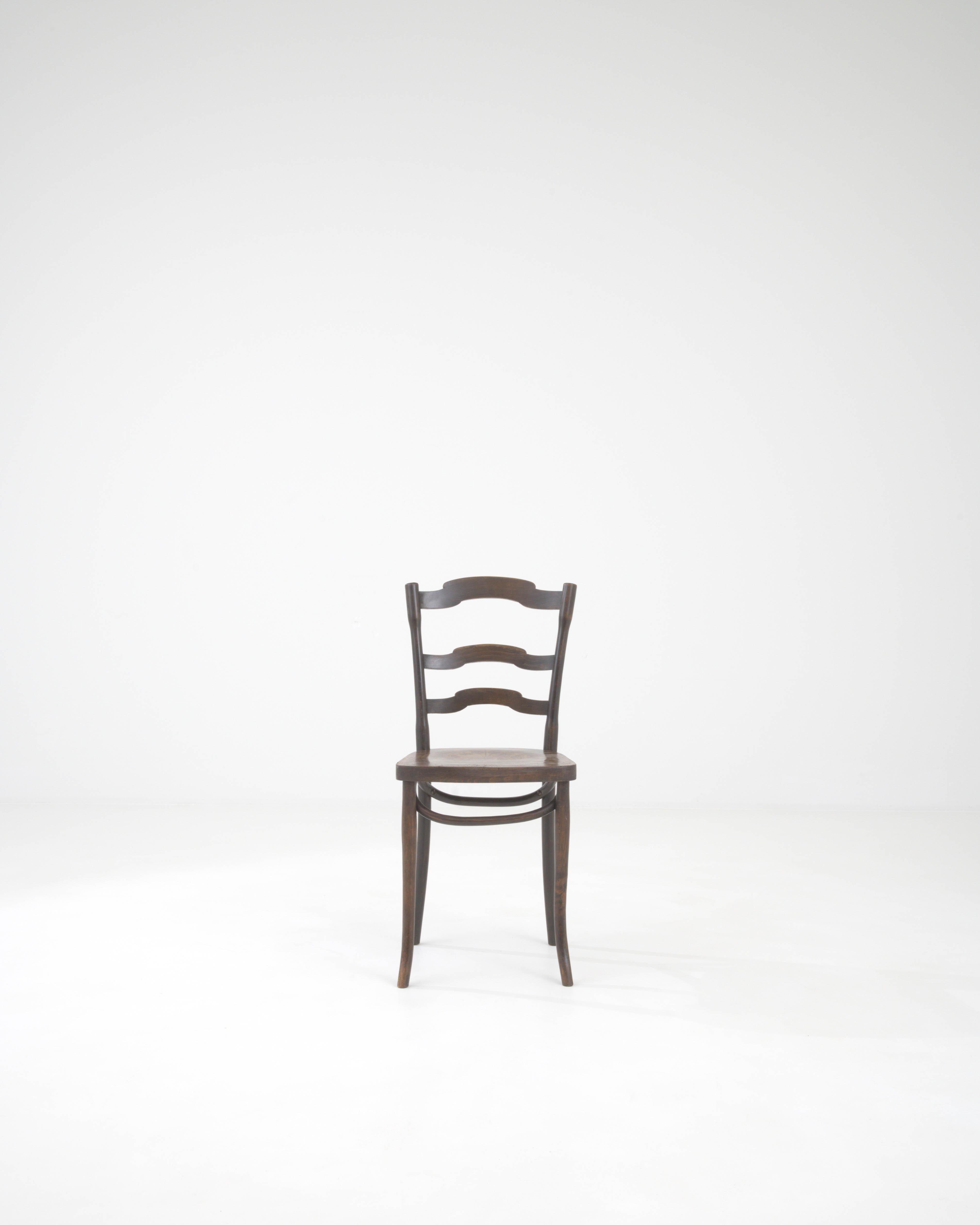 Remontez le temps avec cette exquise chaise de bistrot d'Europe centrale du XXe siècle, une pièce qui capture l'essence de la culture classique des cafés. Son ton de bois chaud et sombre et sa patine gracieusement vieillie racontent une histoire