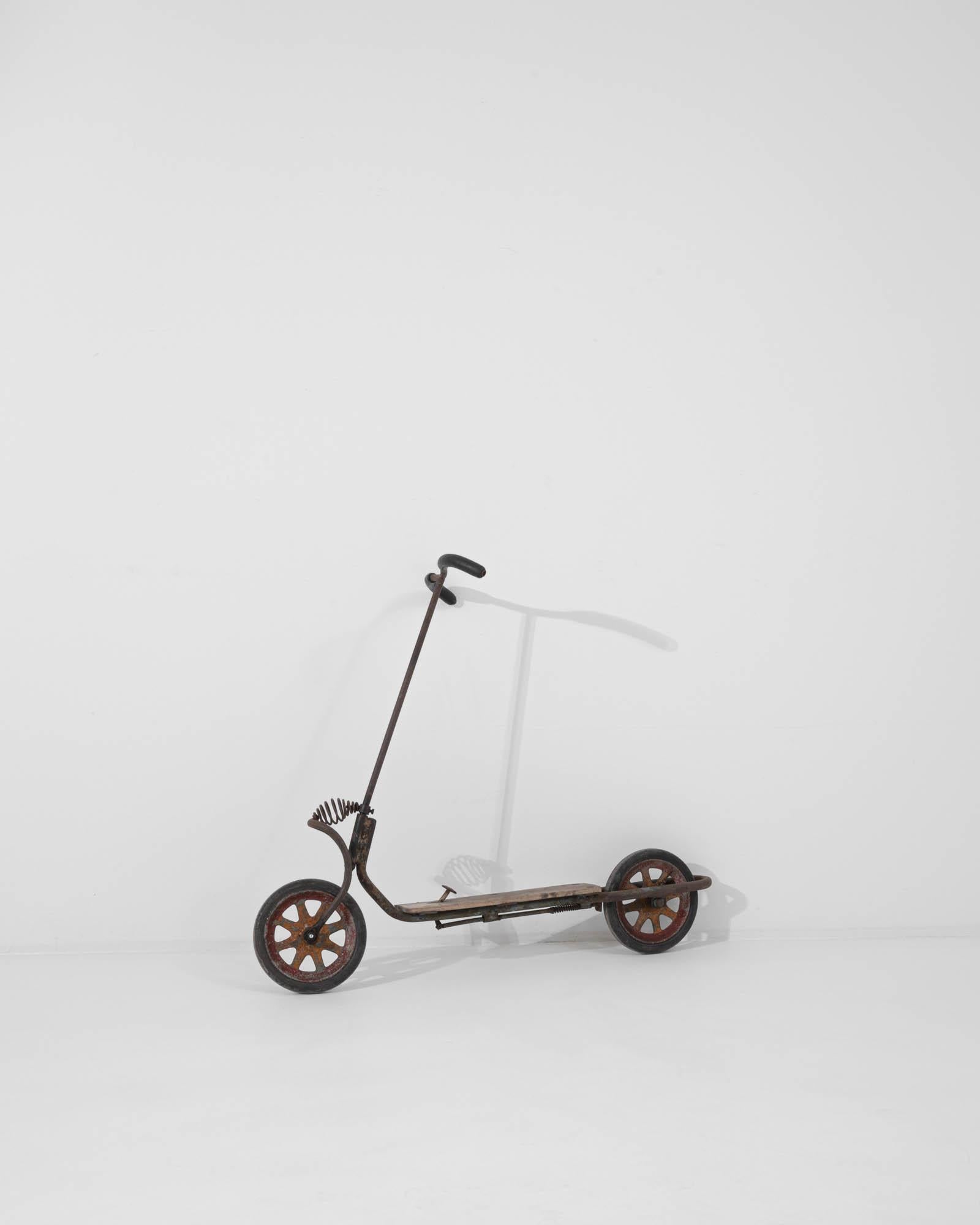 Step back in time with this authentic 20th Century Central European Metal and Wooden Scooter, a whimsical piece that captures the playful spirit of yesteryears. Its sturdy construction features a combination of robust metal and solid wood, telling