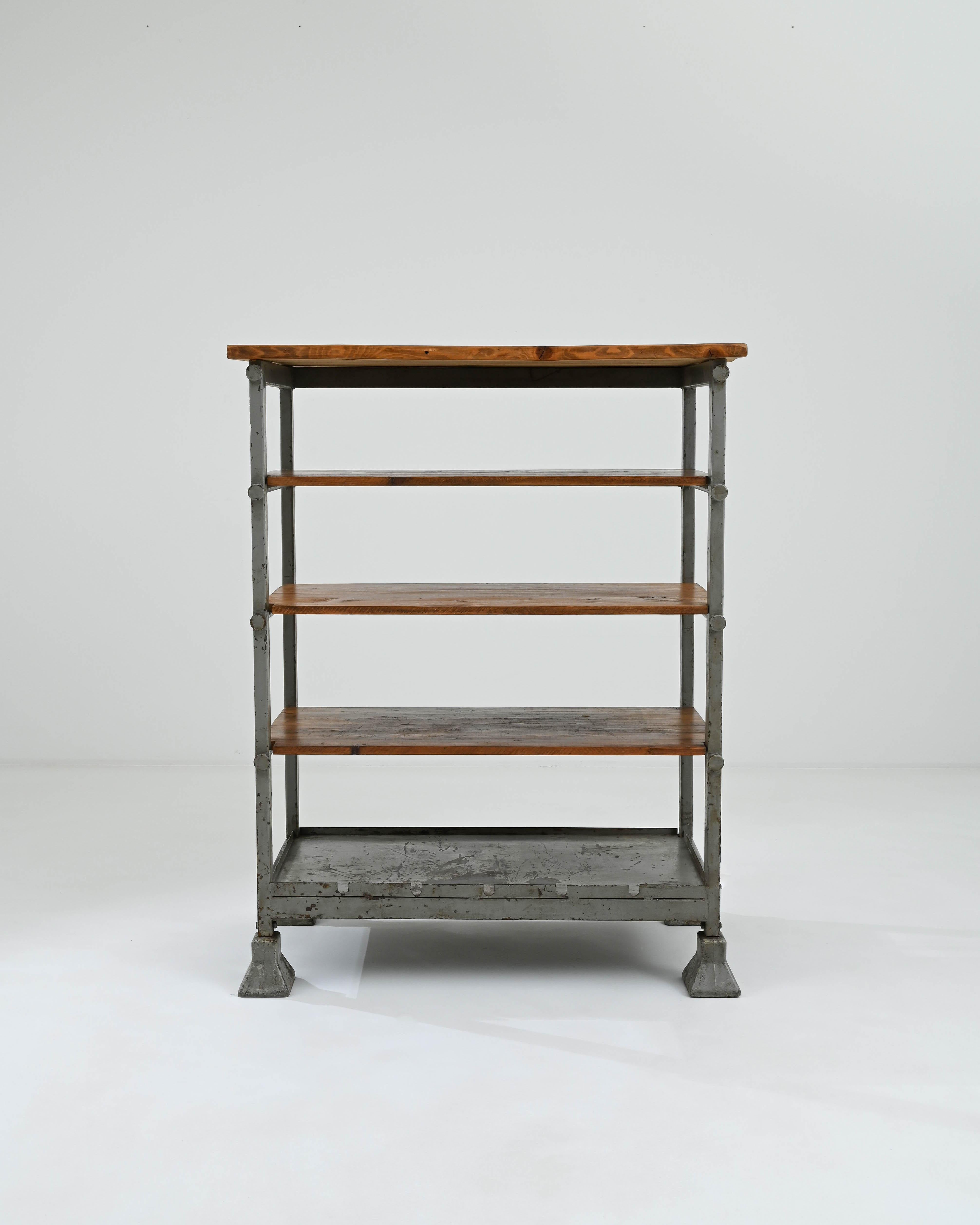 A wooden and metal shelf created in 20th century central Europe. Industrial, yet surprisingly homey, this sturdy set of shelves emits a both utilitarian and approachable aura. Forthright in its design, the four equally sized shelves offer a wealth