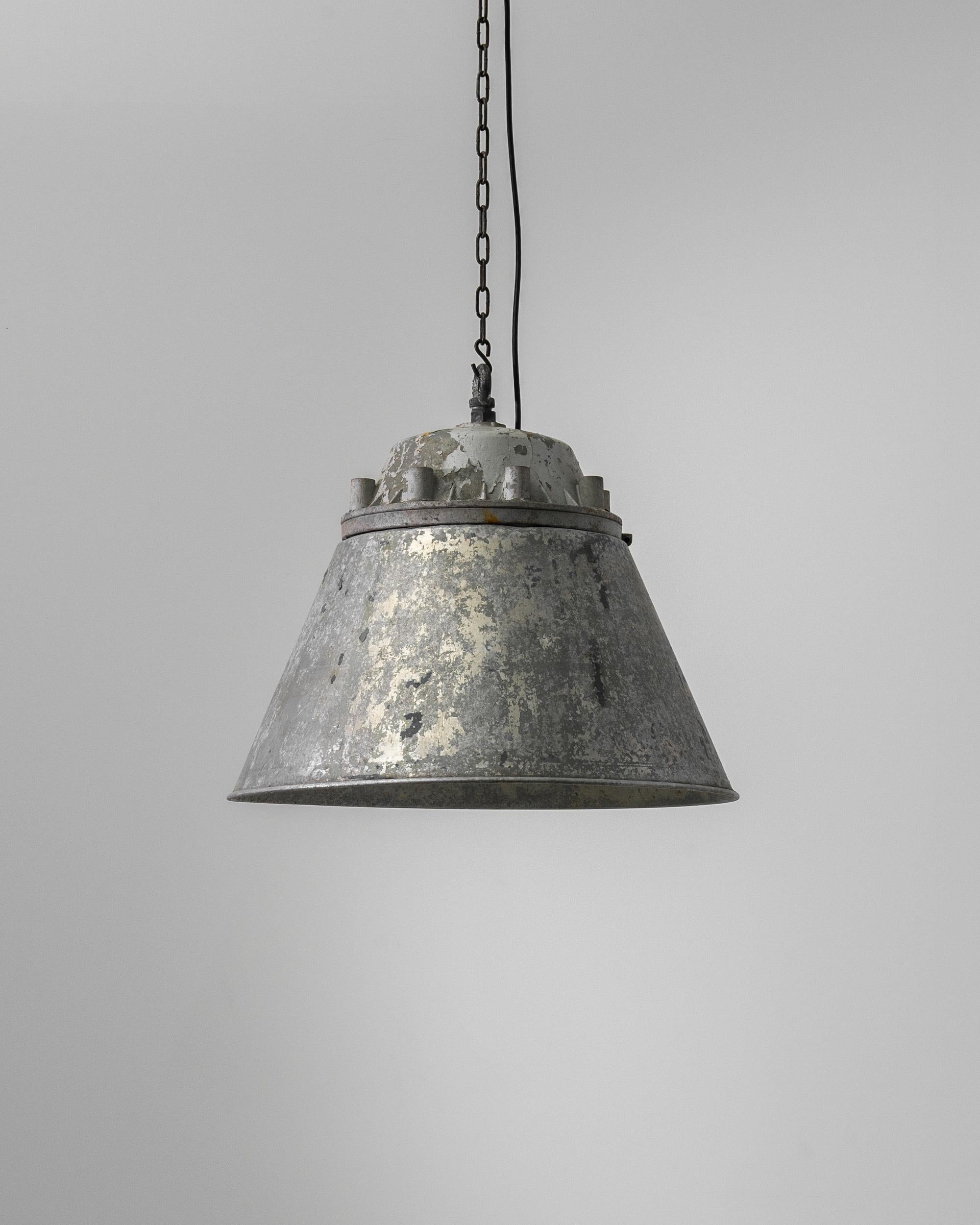 This 20th Century Central European Metal Pendant Lamp is steeped in history and character, offering an industrial aesthetic that is both raw and refined. Its time-weathered surface reveals a life of utility and service, while its sizeable form casts