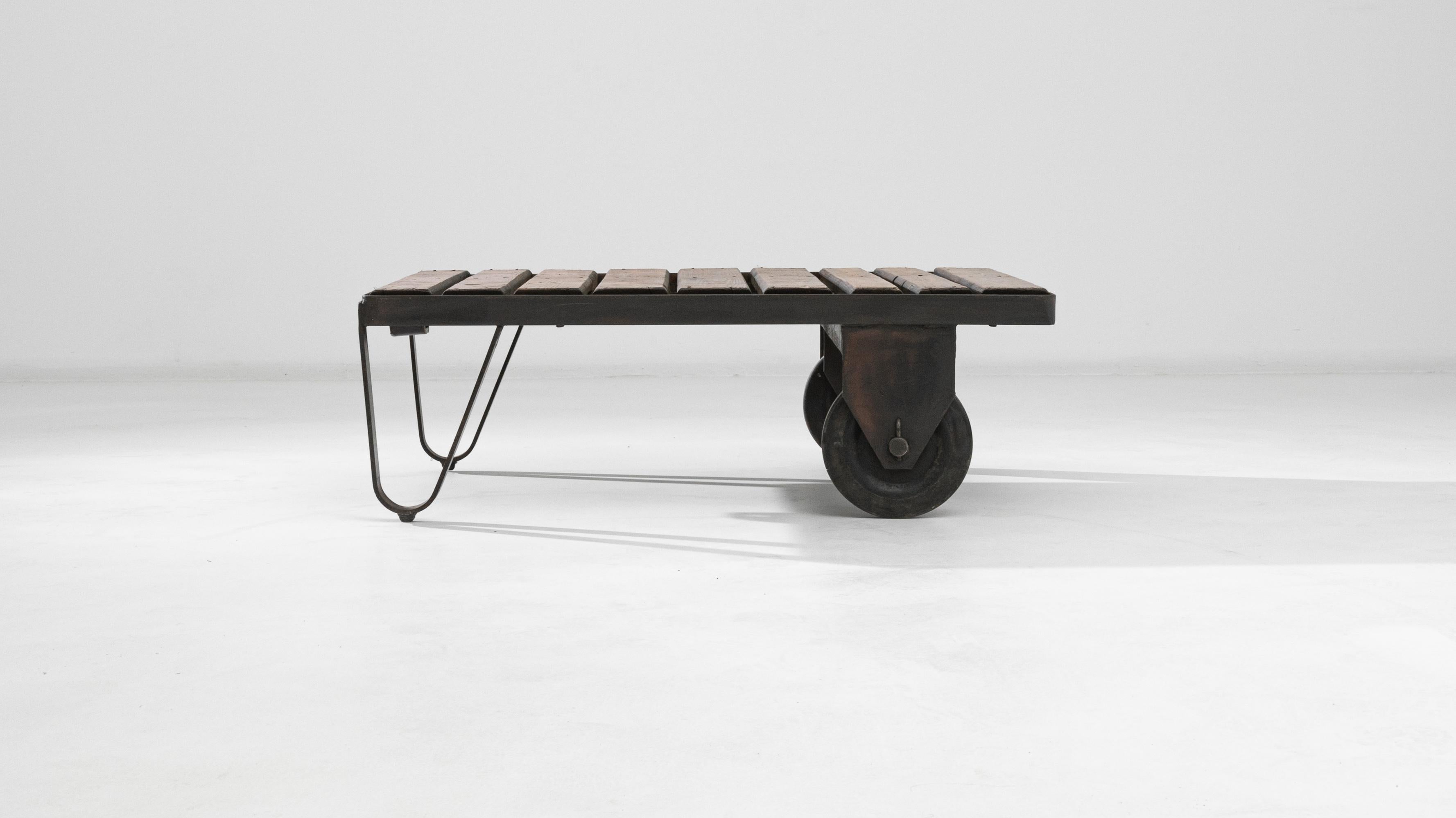 This 20th Century Central European table is a splendid fusion of robust industrial charm and functional design. Mounted on sturdy, aged metal wheels, its portability is a nod to practicality, while the weathered wooden planks breathe rustic life