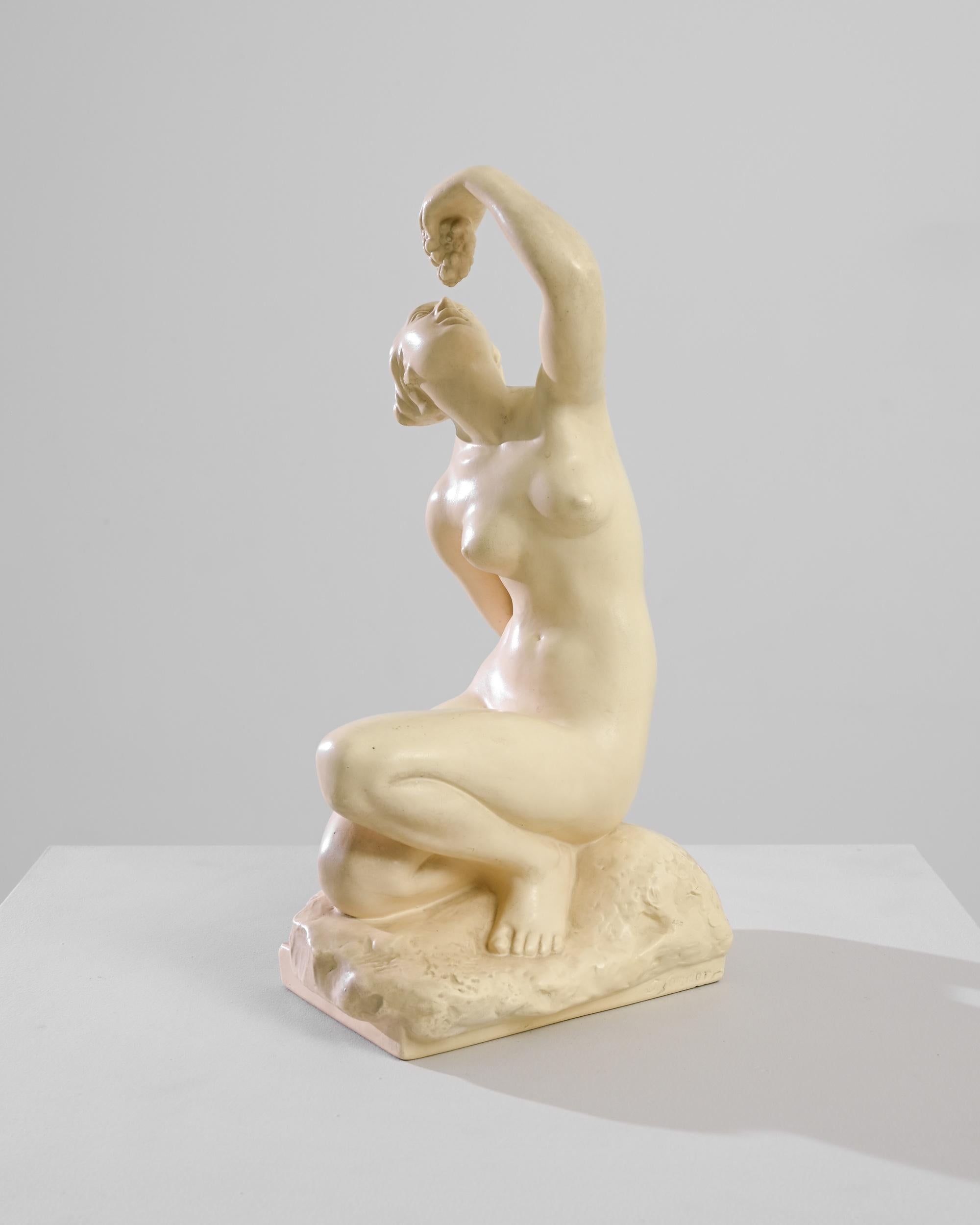 Cette sculpture en plâtre d'Europe centrale du XXe siècle représente une scène intemporelle d'indulgence - une femme en train de manger du raisin. L'élégance du moment est immortalisée dans un plâtre lisse, les courbes et les contours de sa forme