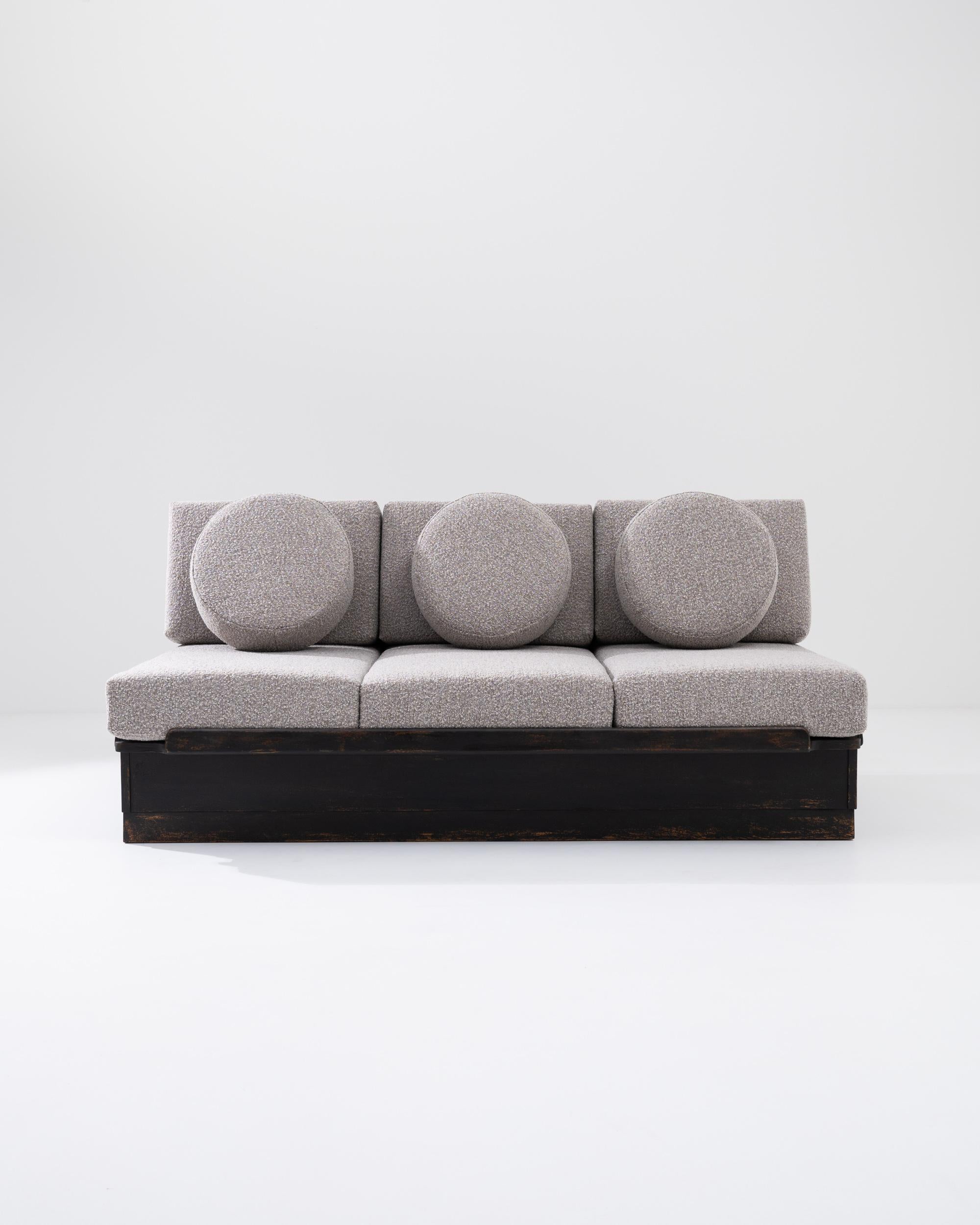 This vintage sofa-bed offers a show-stopping, chic Modernist centerpiece. Made in Central Europe in the 20th century, the straight lines and clean corners of the wooden base are continued in the square cushions of the seat; round pillows add a