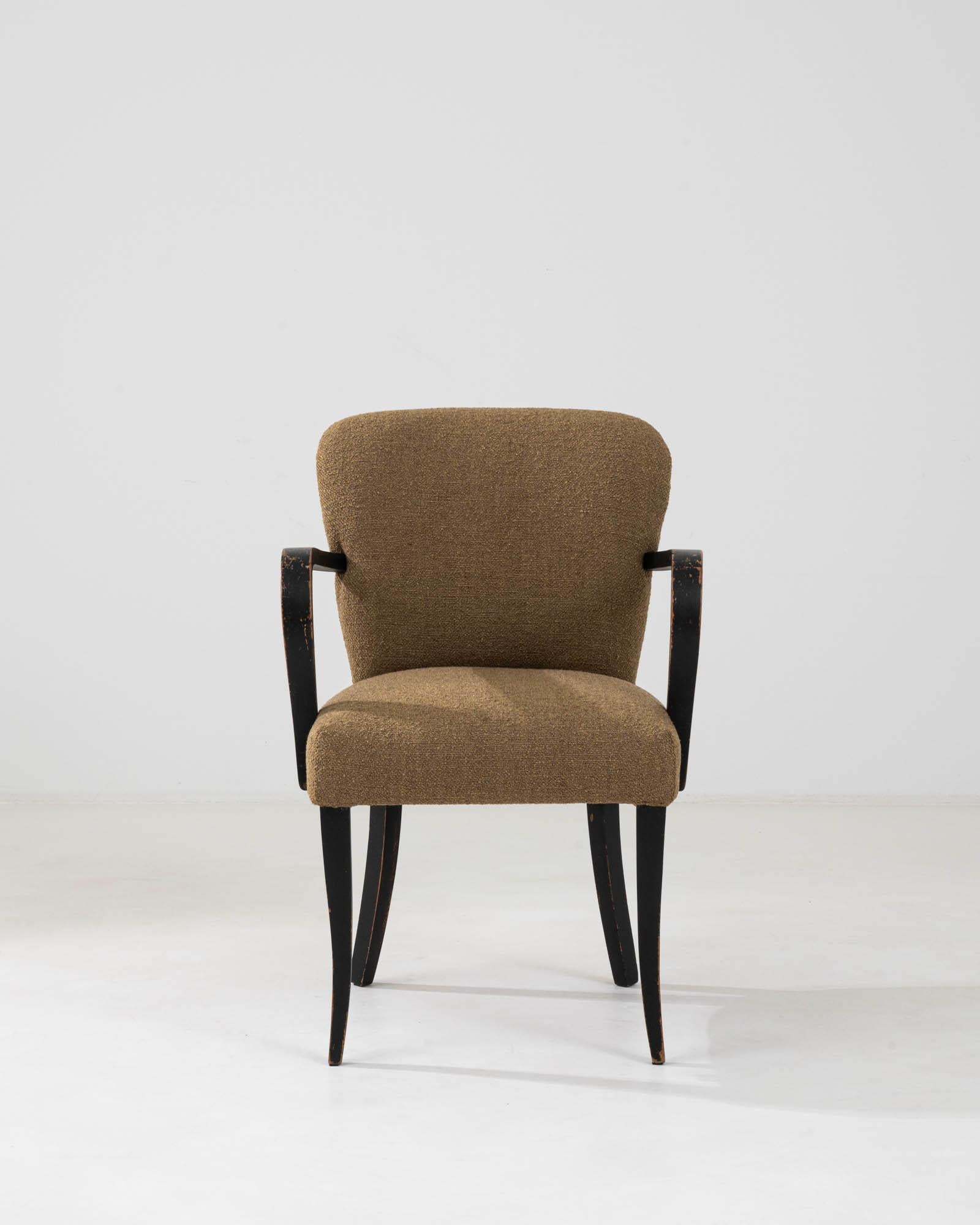 This 20th Century Central European Upholstered Armchair offers a distinctive blend of comfort and vintage style. Upholstered in a durable, earthy brown fabric, it provides a neutral yet elegant palette that complements any interior. The chair