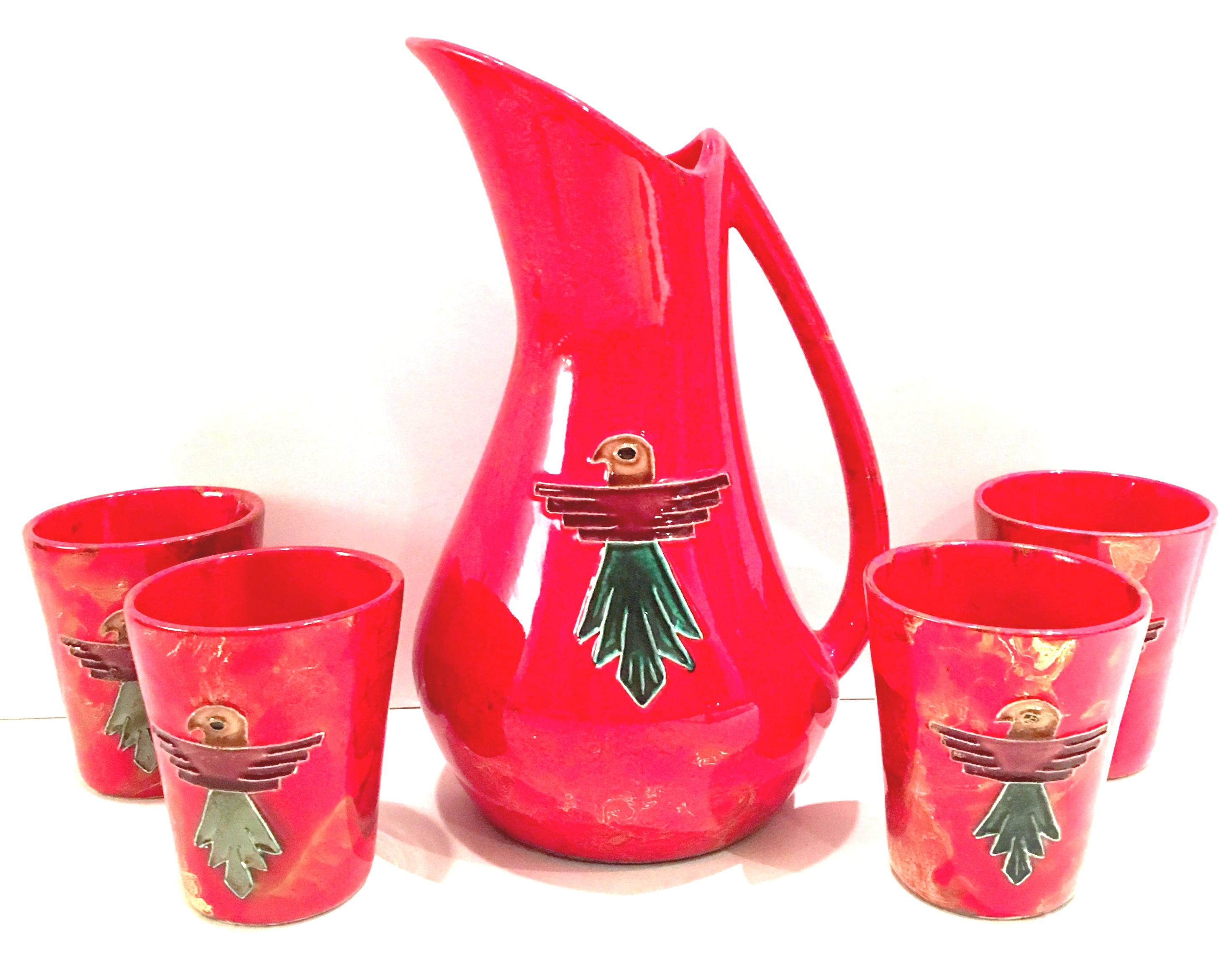 Mid-Century fire engine red with gold metallic detail and reposse thunderbird hand-painted detail five piece drinks set. Set includes handled pitcher and four tumblers. Tumblers measure, 4