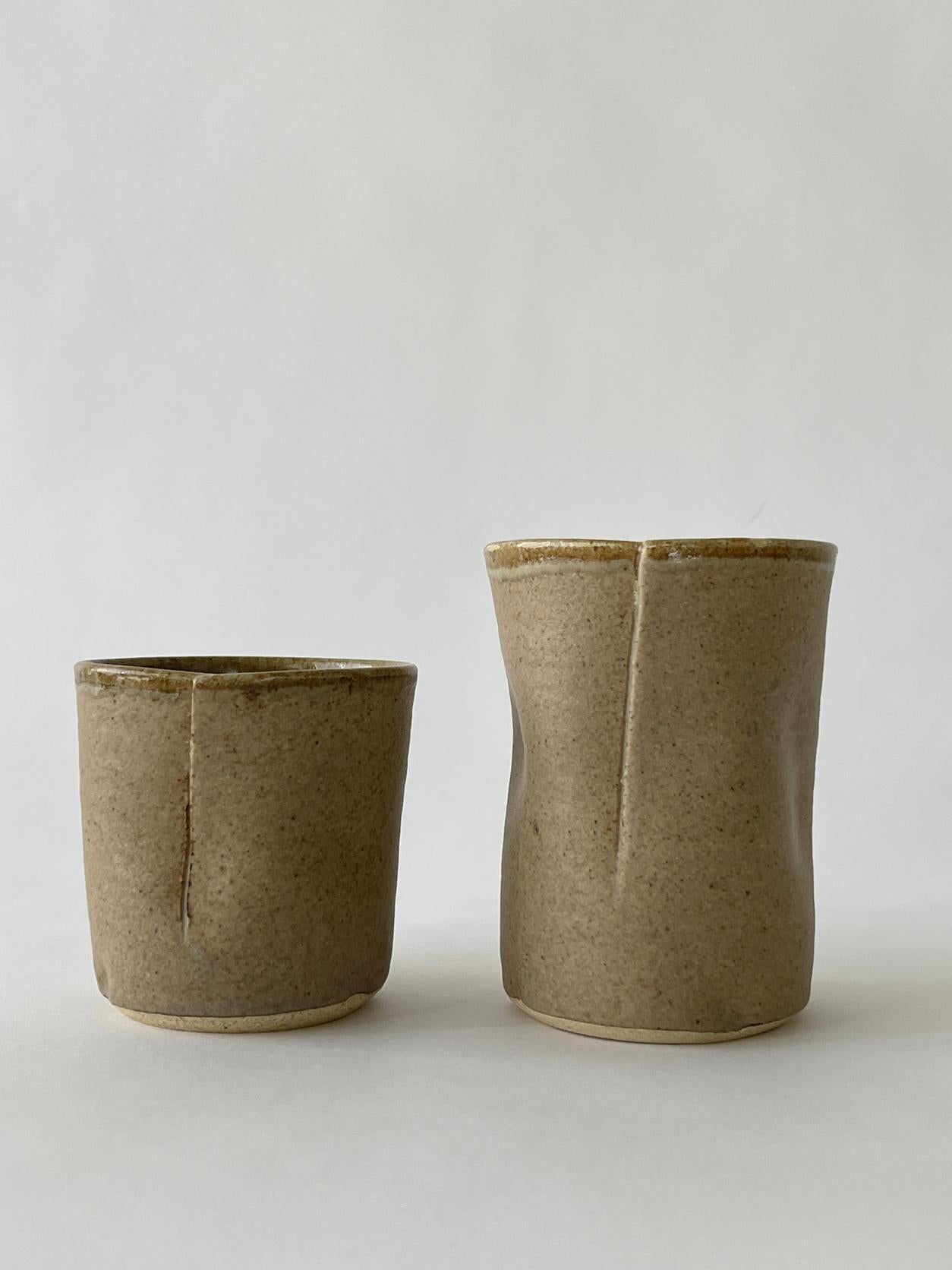 20th century Ceramic handcrafted cup set in a beautiful neutral tan/brown color. Fold over design with a matte exterior finish and a glazed inside. 

Measures: Larger cup: 3.75