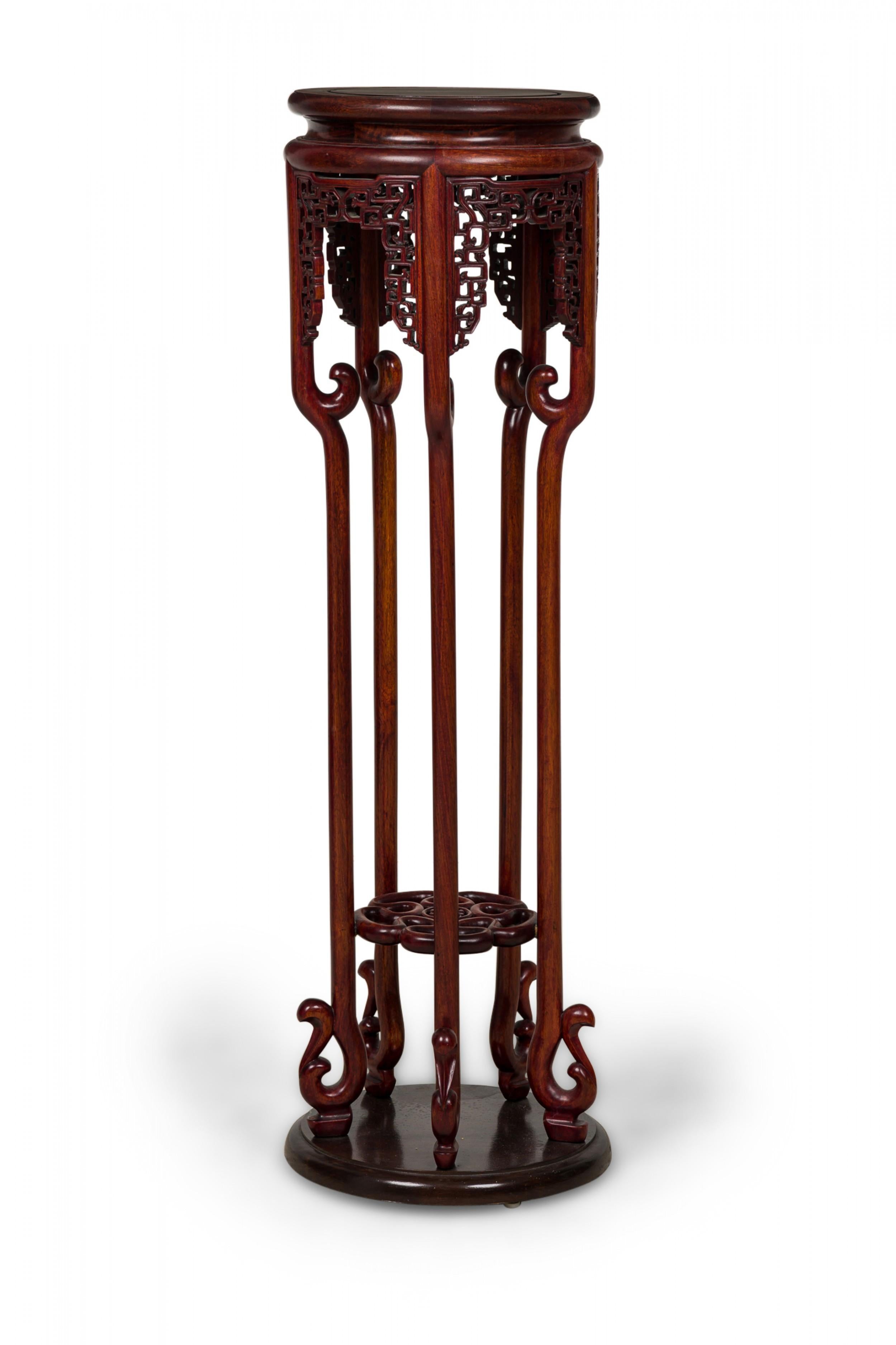Guéridon / table chinoise (20e siècle) en bois sculpté présentant un plateau circulaire cintré suivi d'un tablier ajouré mouluré à motif de volutes géométriques, reposant sur cinq pieds courbés supportant une étagère inférieure à volutes ajourées et