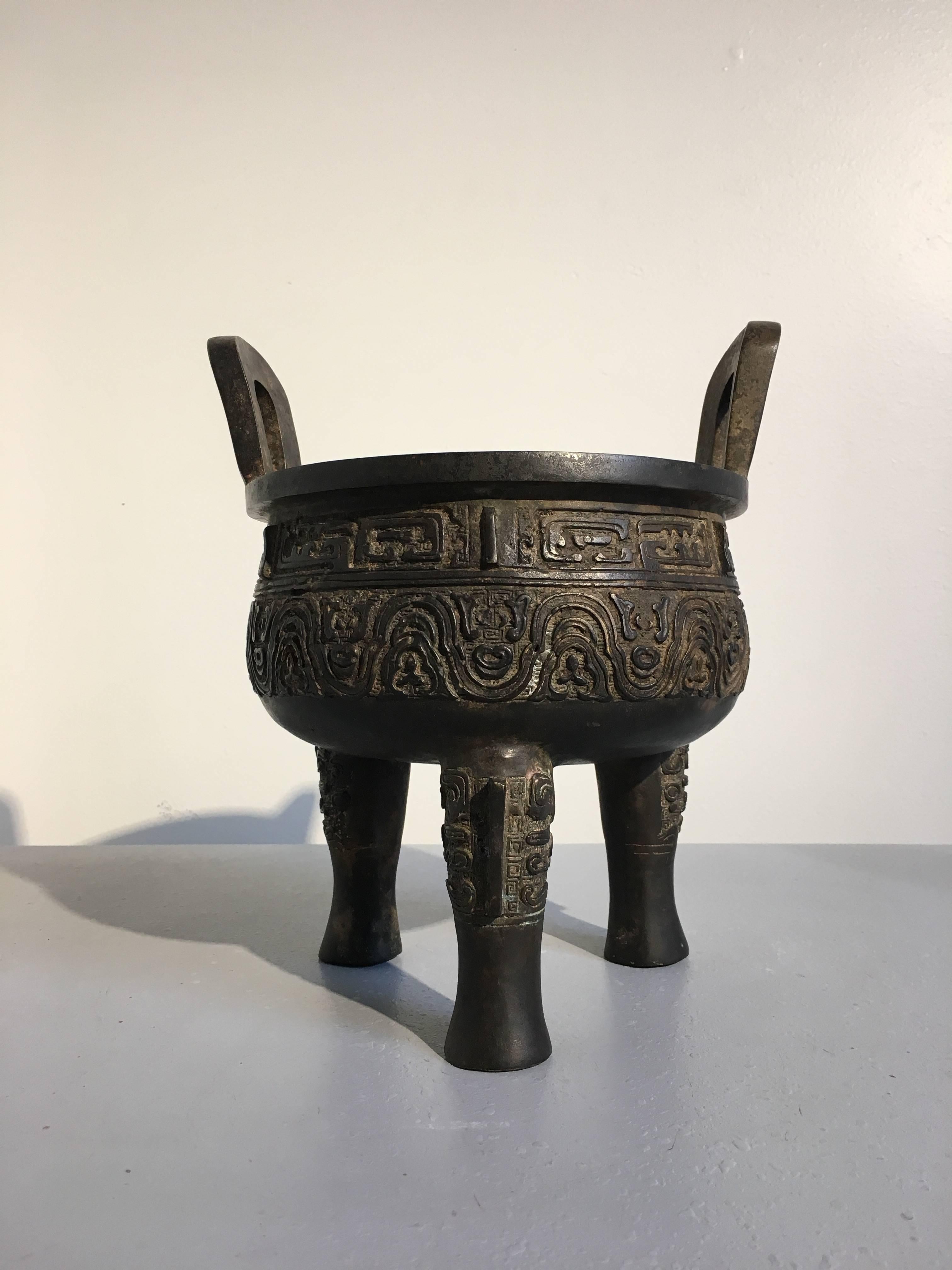 A well cast Chinese archaistic bronze tripod censer, ding, in the Ming style, Republic Period, early 20th century, China.

Heavily cast in the archaistic style, seemingly inspired by Ming Dynasty archaistic bronzes, the ding sits on long tripod legs