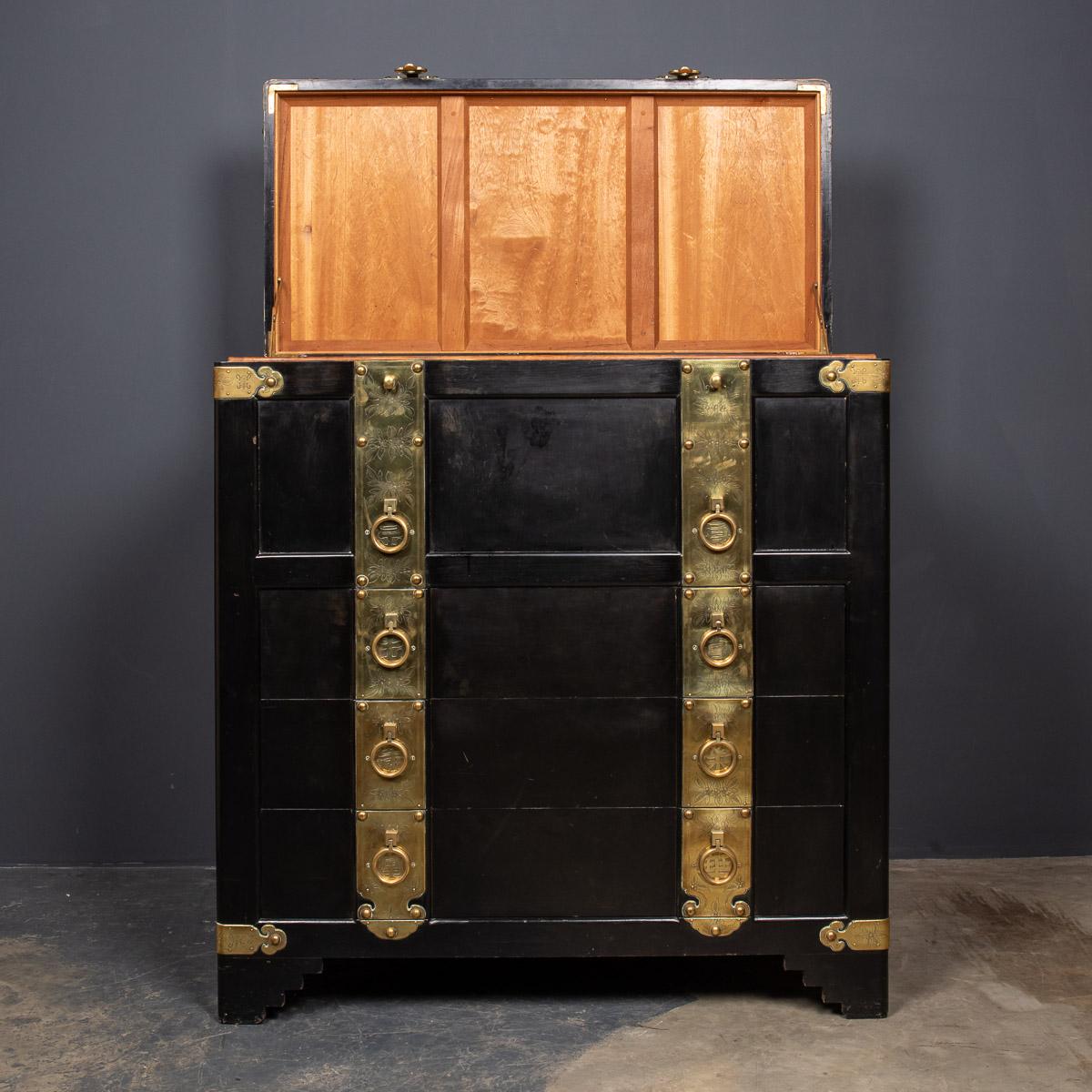 Striking mid-20th century Chinese export black lacquered trunk with engraved brass banding and handles. The top trunk is lined with cedar and the insides of the drawers have been ebonised.

Measures: Width 107cm
Height 101cm
Depth 50cm.