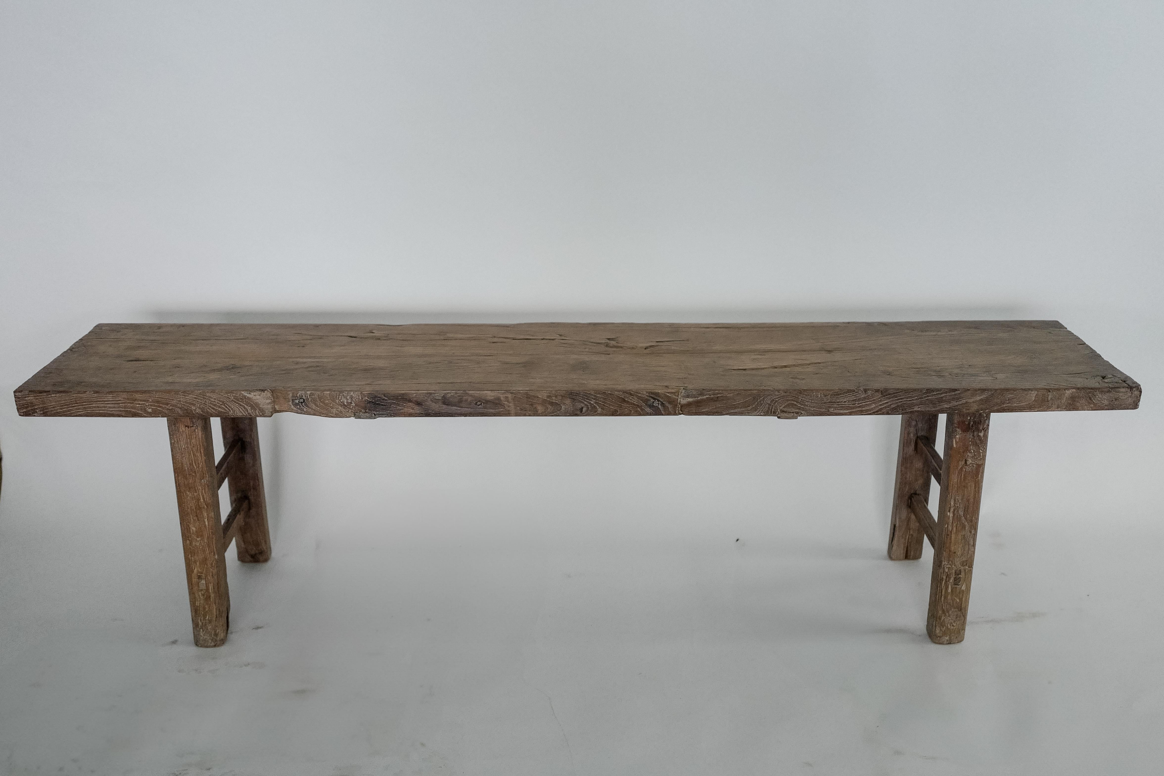 Ce banc en orme chinois du XXe siècle incarne un design rustique et minimaliste qui met en valeur la beauté naturelle du bois d'orme massif. Avec ses tons terreux et ses motifs de grain distinctifs, ce banc ajoute de la chaleur et du caractère à