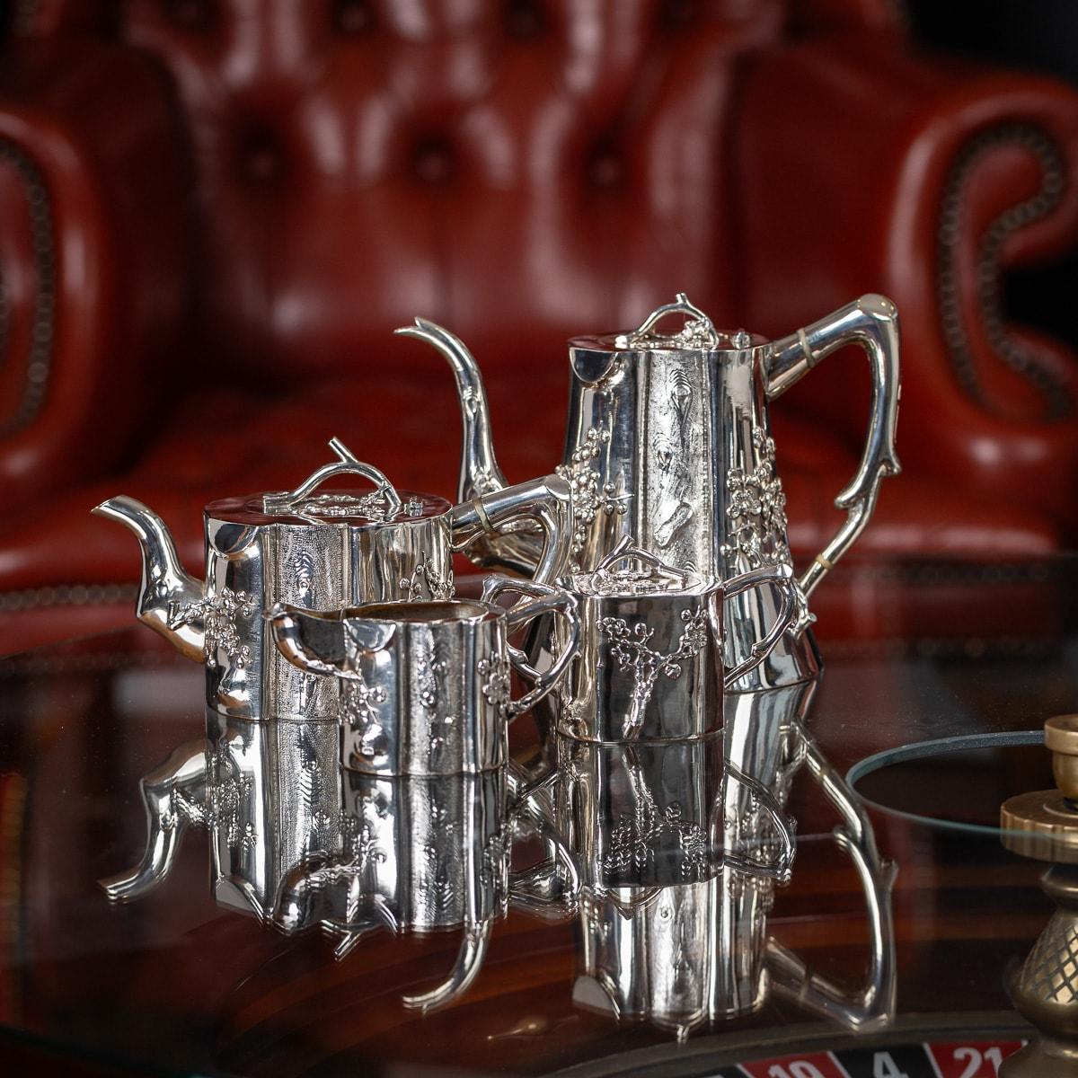 Antique early-20th Century Chinese export solid silver four piece tea set, comprising of a coffee pot, teapot, sugar pot and milk jug, each tree-trunk shaped body applied with prunus flowers and applied with decoration in relief, spout, handles and