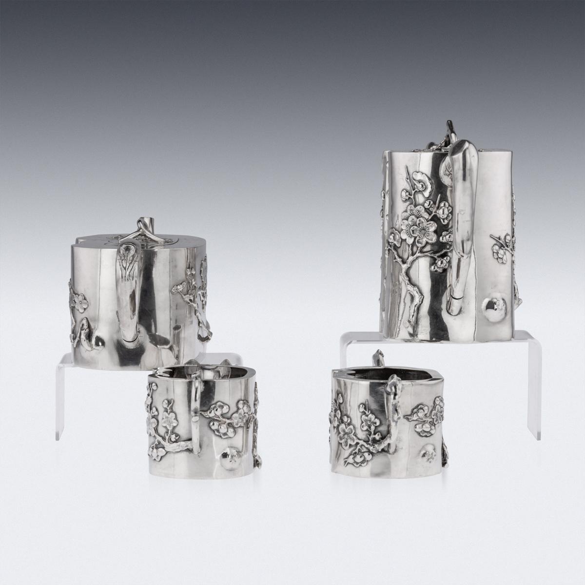20th Century Chinese export silver four piece tea set, comprising of a coffee pot, teapot, sugar bowl and milk jug, each tree-trunk shaped body applied with prunus flowers and applied with decoration in relief, spout, handles and finials modelled as