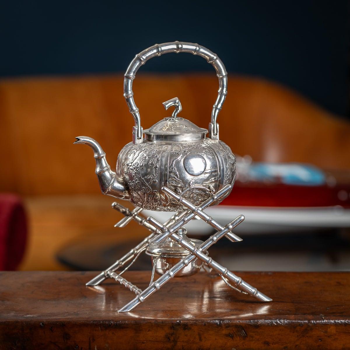 Antique early 20th century Chinese export solid silver tea kettle on stand, the body chased in relief with floral decoration, the domed lids mounted with a bamboo finial. The kettle is suspended on a stylised, well constructed bamboo stand, with a