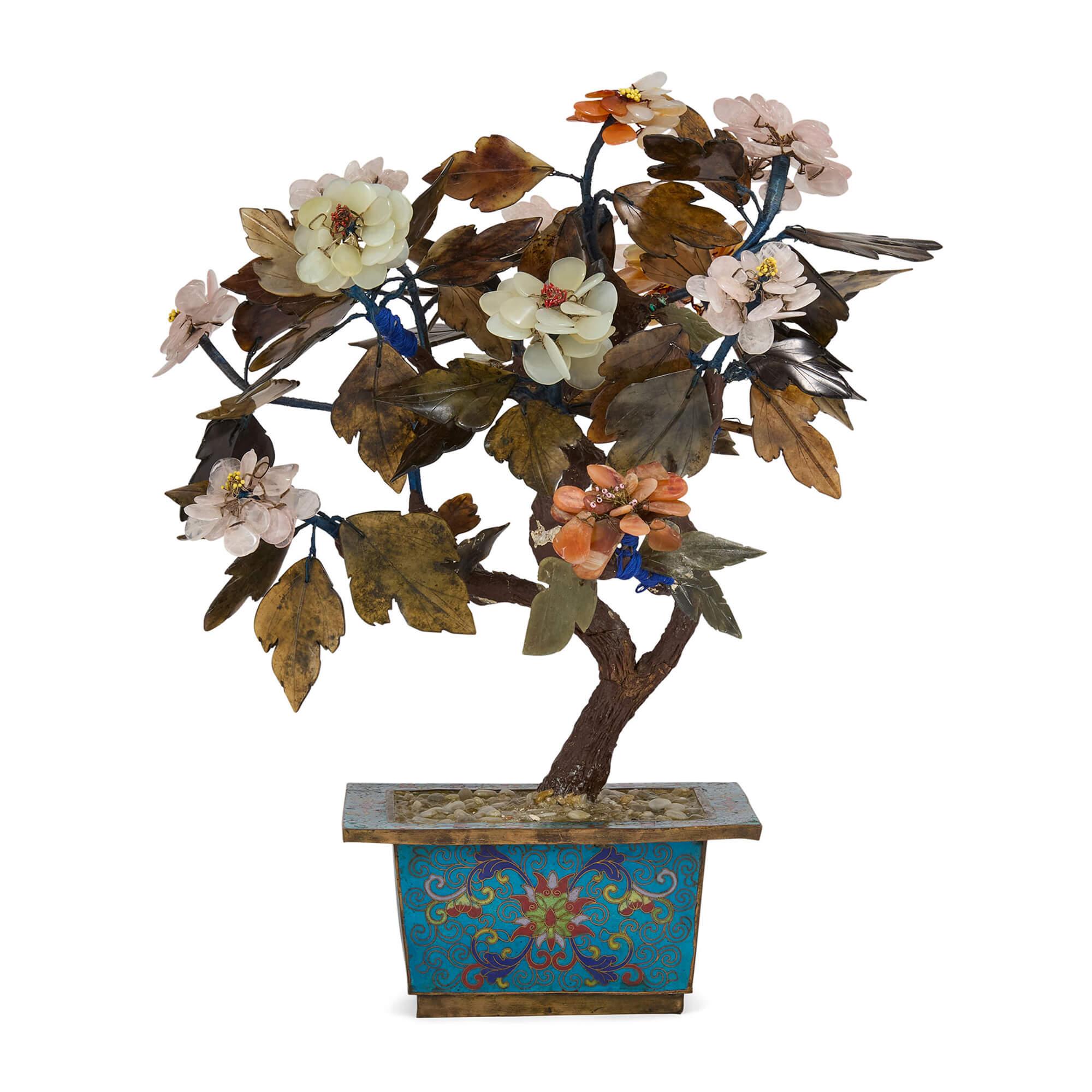20th century Chinese hardstone flowering tree in a cloisonné planter
Chinese, 20th century
Height 42cm, width 33cm, depth 31cm

This exquisite 20th-century Chinese hardstone tree is a beautiful fusion of artistic skill and cultural symbolism.