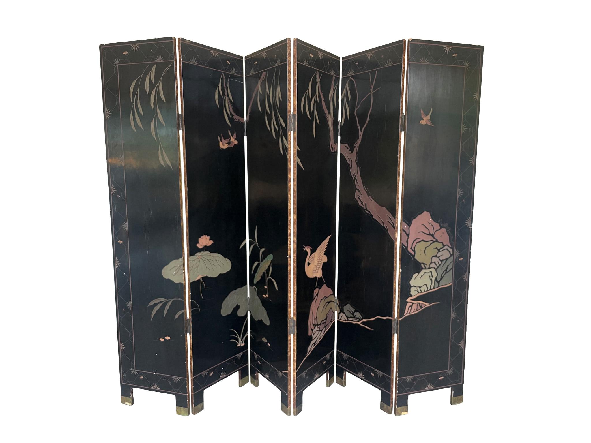 This richly designed Chinese folding screen consists of 6 individual panels. It was made in the 2nd quarter of the 20th Century. One side has a black lacquered ground that unfolds a dark, quiet landscape of birds and foliage. The other side unfolds
