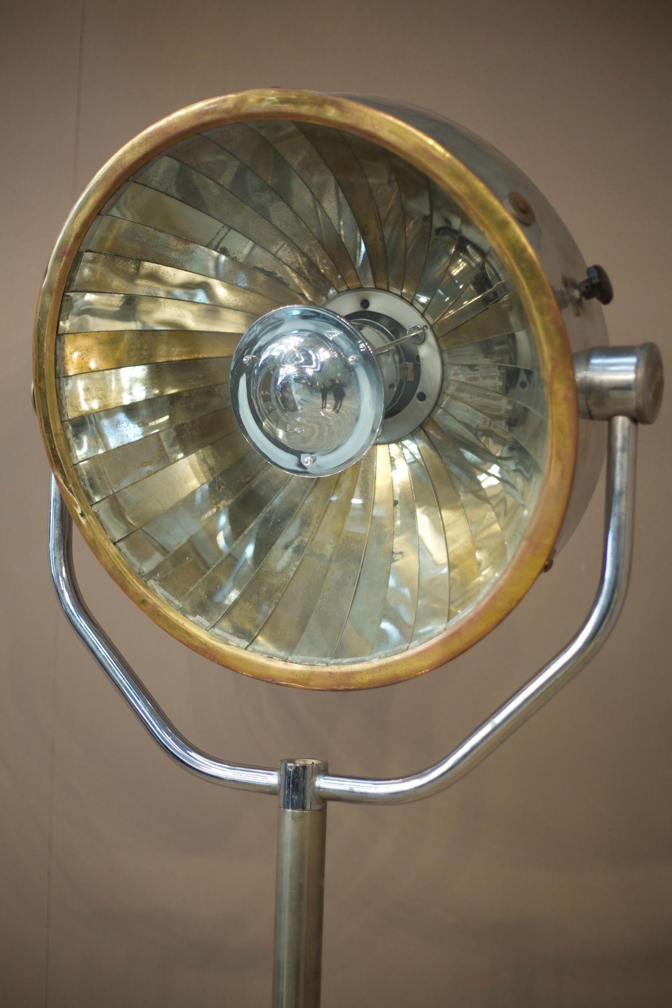This is a spectacular 20th century chrome floor lamp. Originally I believe this to have been a medial light as the segmented mirror plates in the light itself cast a very attractive directional light. The brass rim around the light give this a very