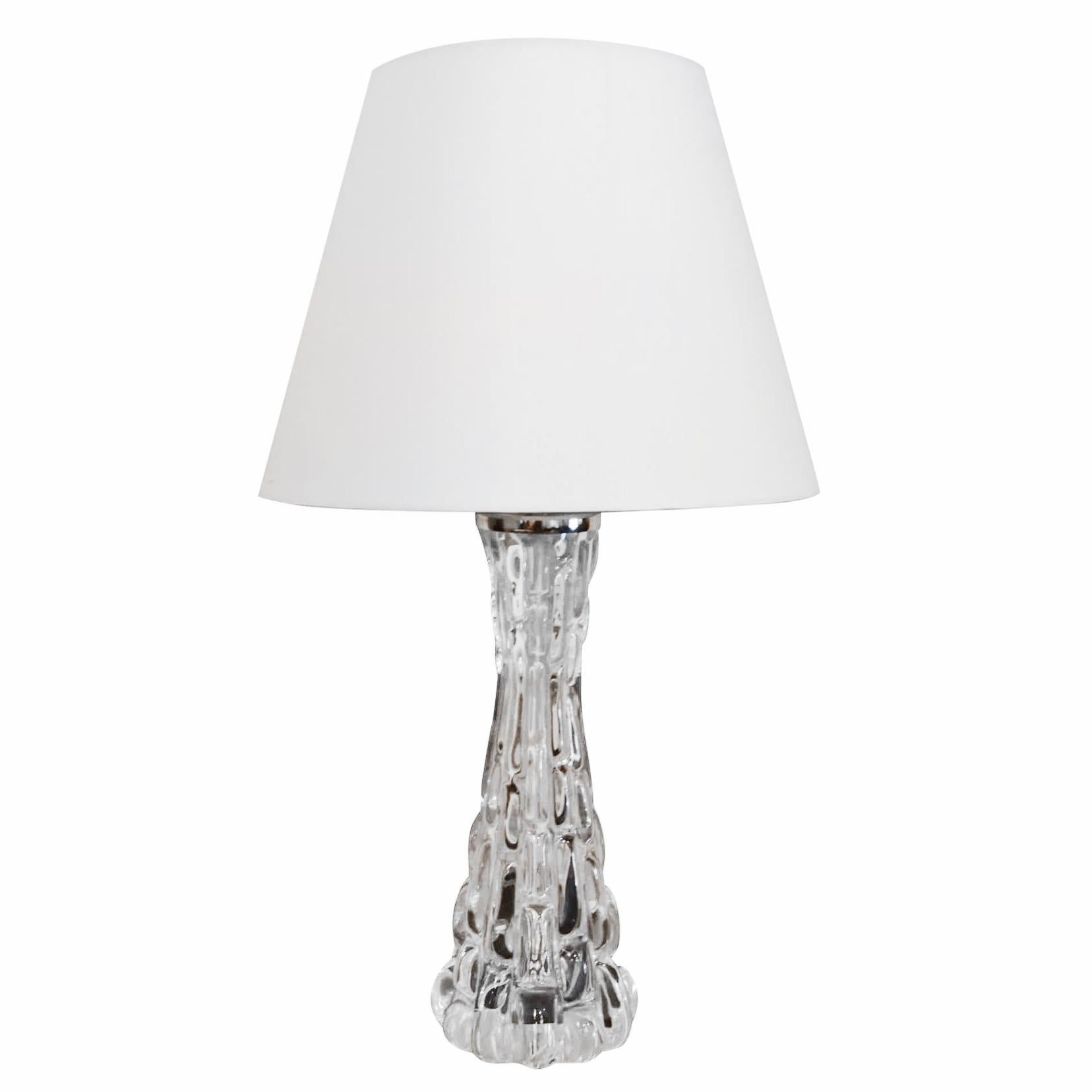 A vintage Mid-Century Modern Swedish table lamp made of hand blown Orrefors, cut glass with a white shade, featuring a one light socket. The Scandinavian desk light was designed by Carl Fagerlund and produced by Orrefors, in good condition. Signed