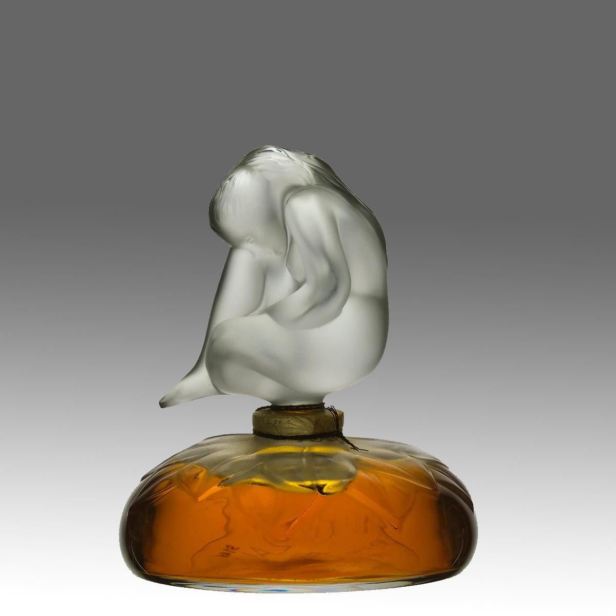 An excellent clear and frosted glass scent bottle by Lalique. The dome shape scent bottle etched with petals and full with original Lalique perfume with decorative stopper in the form of a seated woman with knee raised, signed Lalique France and