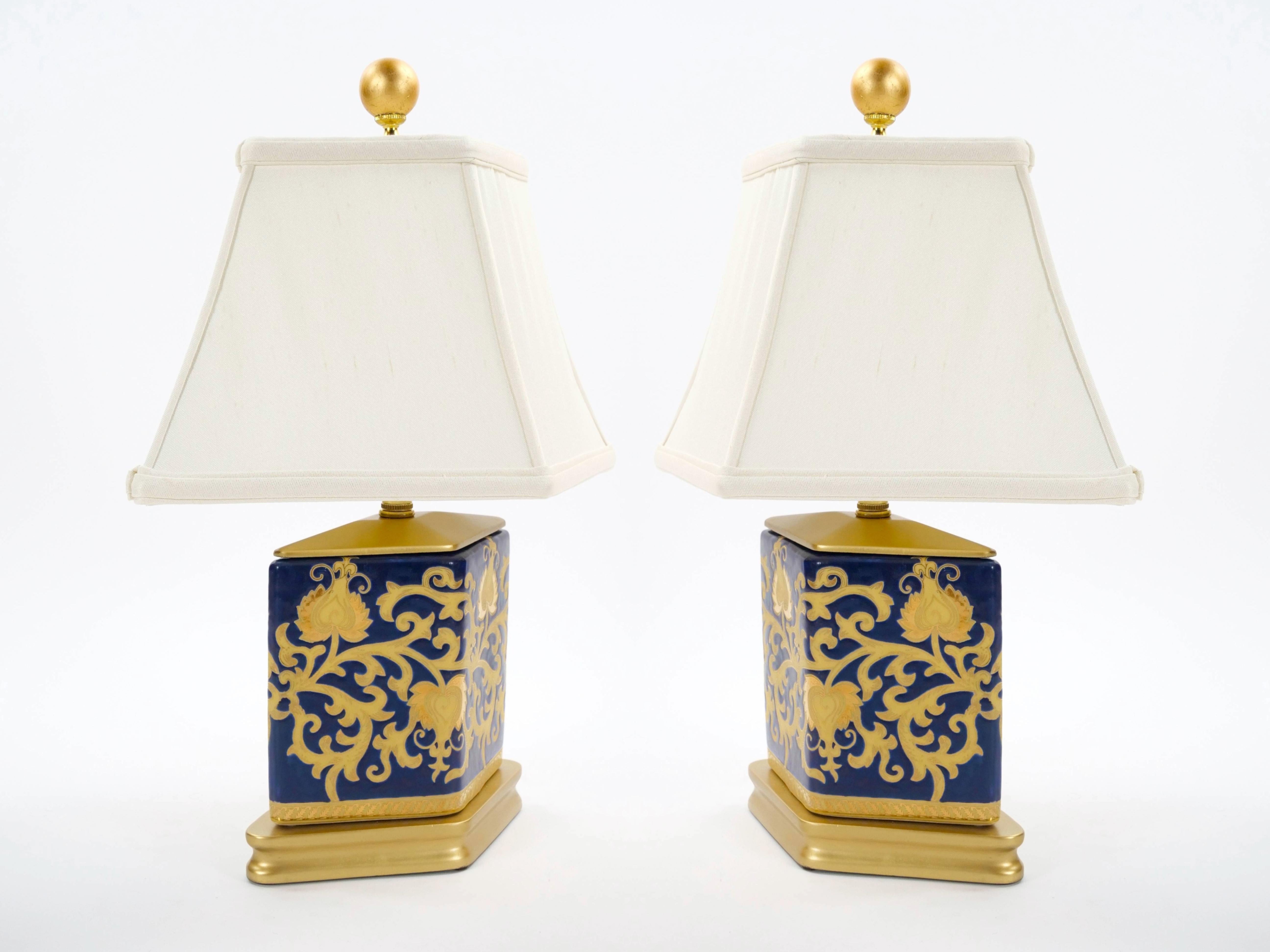 Esta exquisita lámpara de sobremesa del siglo XX presenta un llamativo cuerpo de porcelana azul cobalto, bellamente adornado con un diseño de tapicería dorada que añade un toque de lujo y elegancia. La lámpara presenta una forma geométrica de jarrón