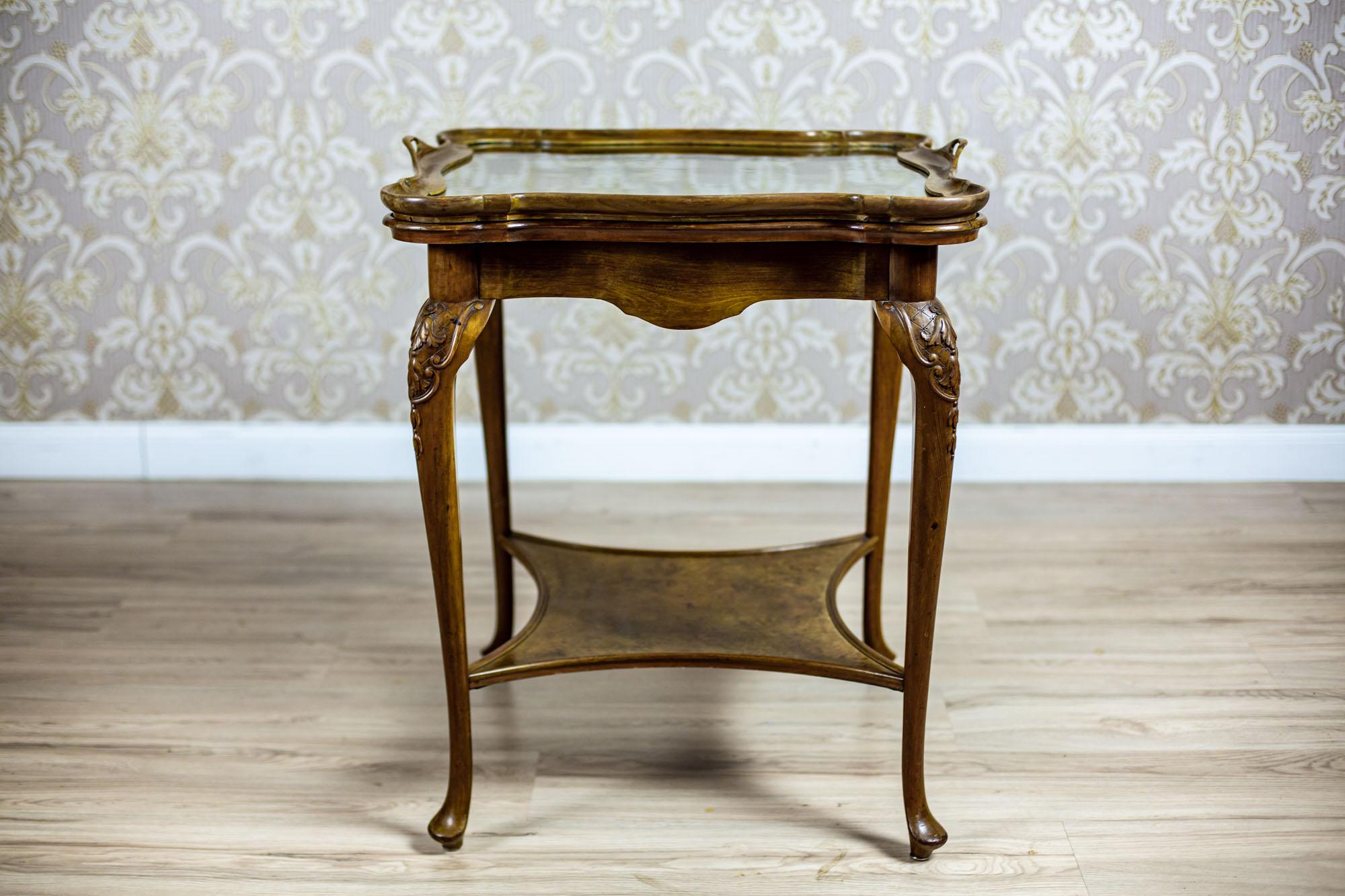 We present you a square coffee table with a removable tray.
All is dated after the year 1945.
The table top is supported on bent legs with protruding knees, which are covered with carved patterns.
Furthermore, the legs are connected at the bottom