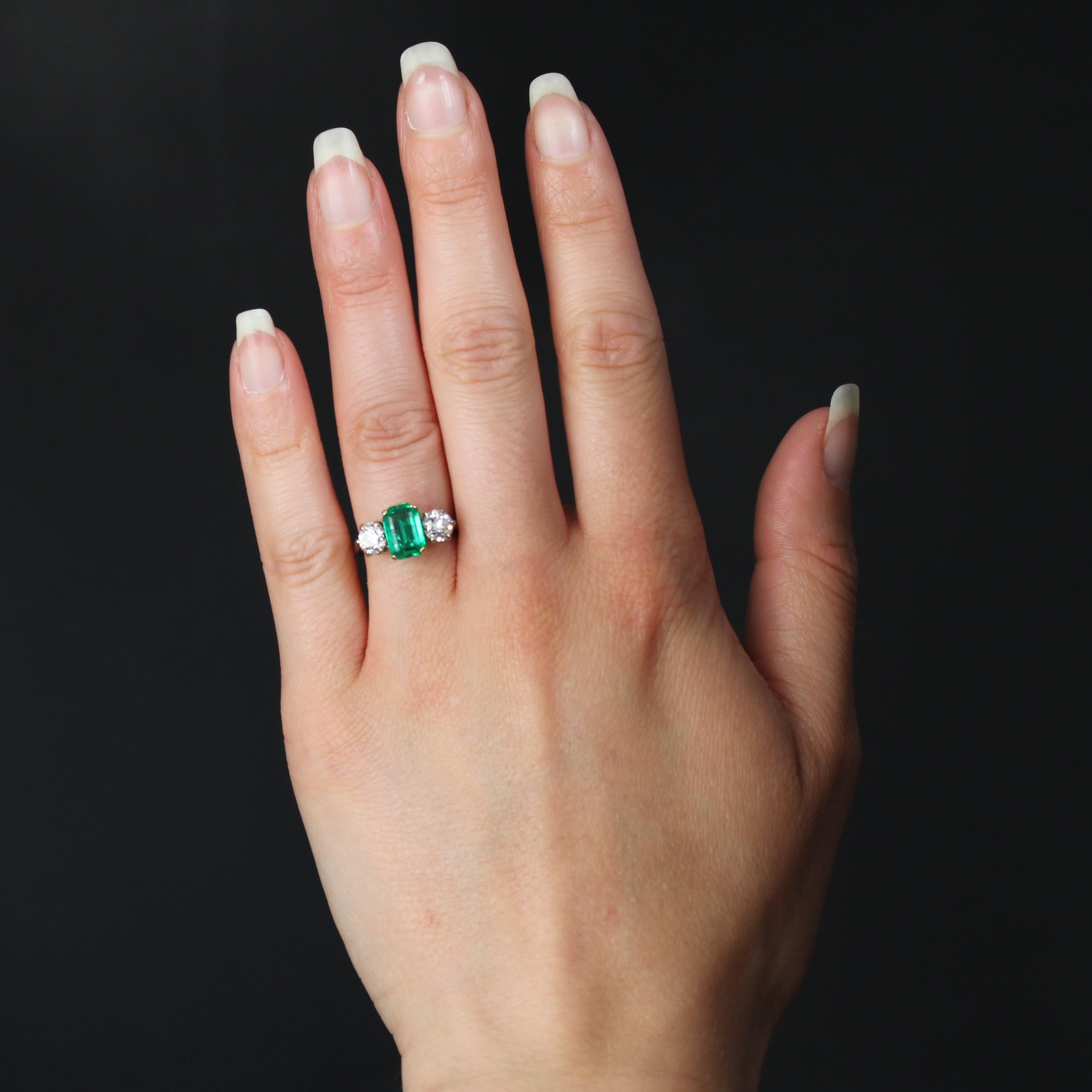Ring in 18 karat white and yellow gold, owl hallmark.
It is decorated on its top with an degrees- cut emerald retained with 4 claws and shouldered on both sides of 2 antique brilliant- cut diamonds, also retained with claws. The profile is