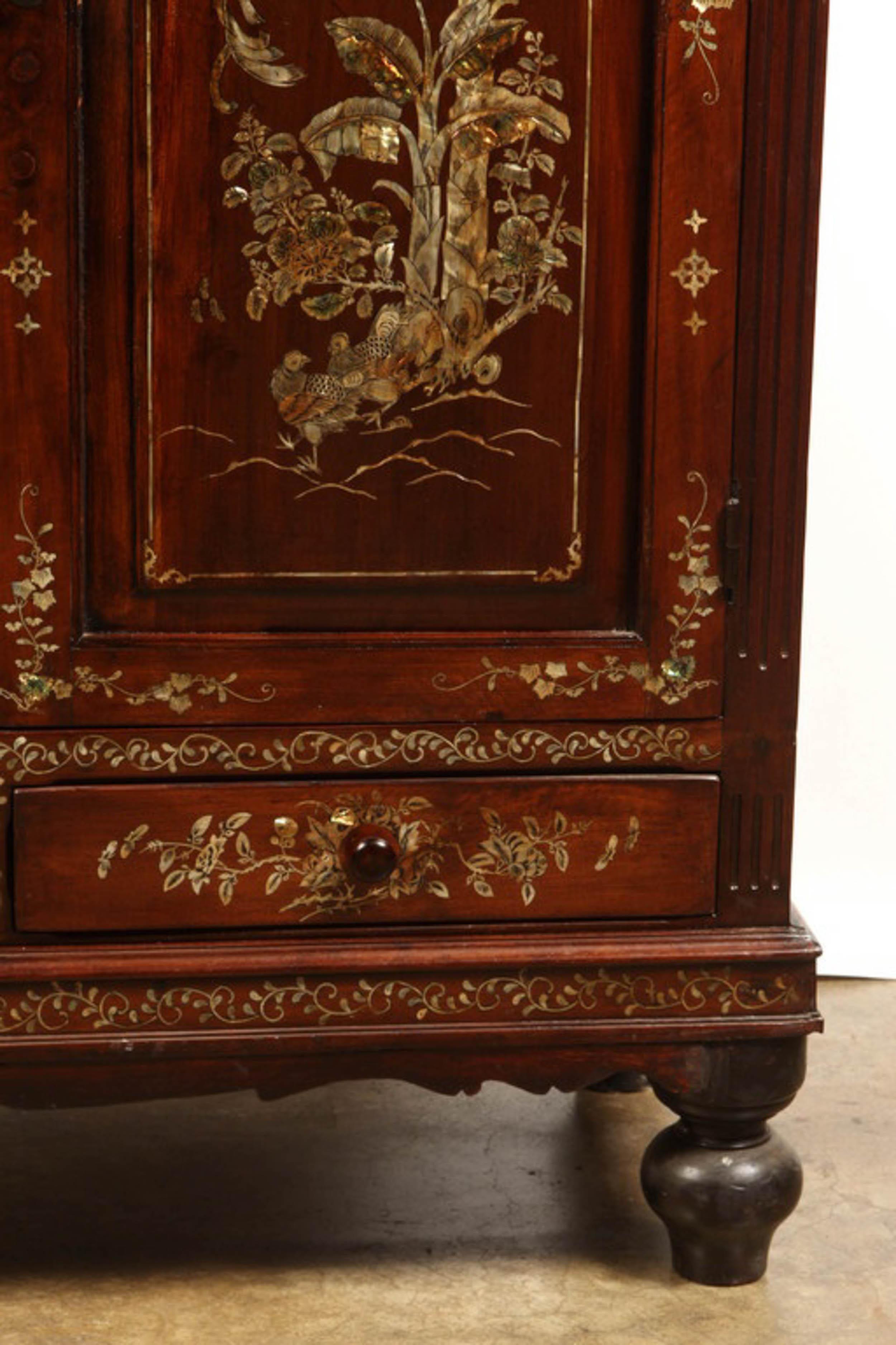 A solid rosewood cabinet with the front richly inlaid with mother of pearl depicting palm trees and birds. Made in Vietnam for the export market. The two doors open to reveal a compartment divided by a single shelf, over two drawers. All on four