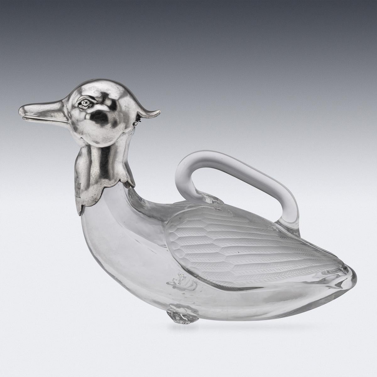 A superb 20th Century Continental solid silver & clear glass novelty claret jug, realistically modelled as a duck with its head slightly raised, with a silver sprung-hinged head. The clear glass body with handle attached is realistically modelled