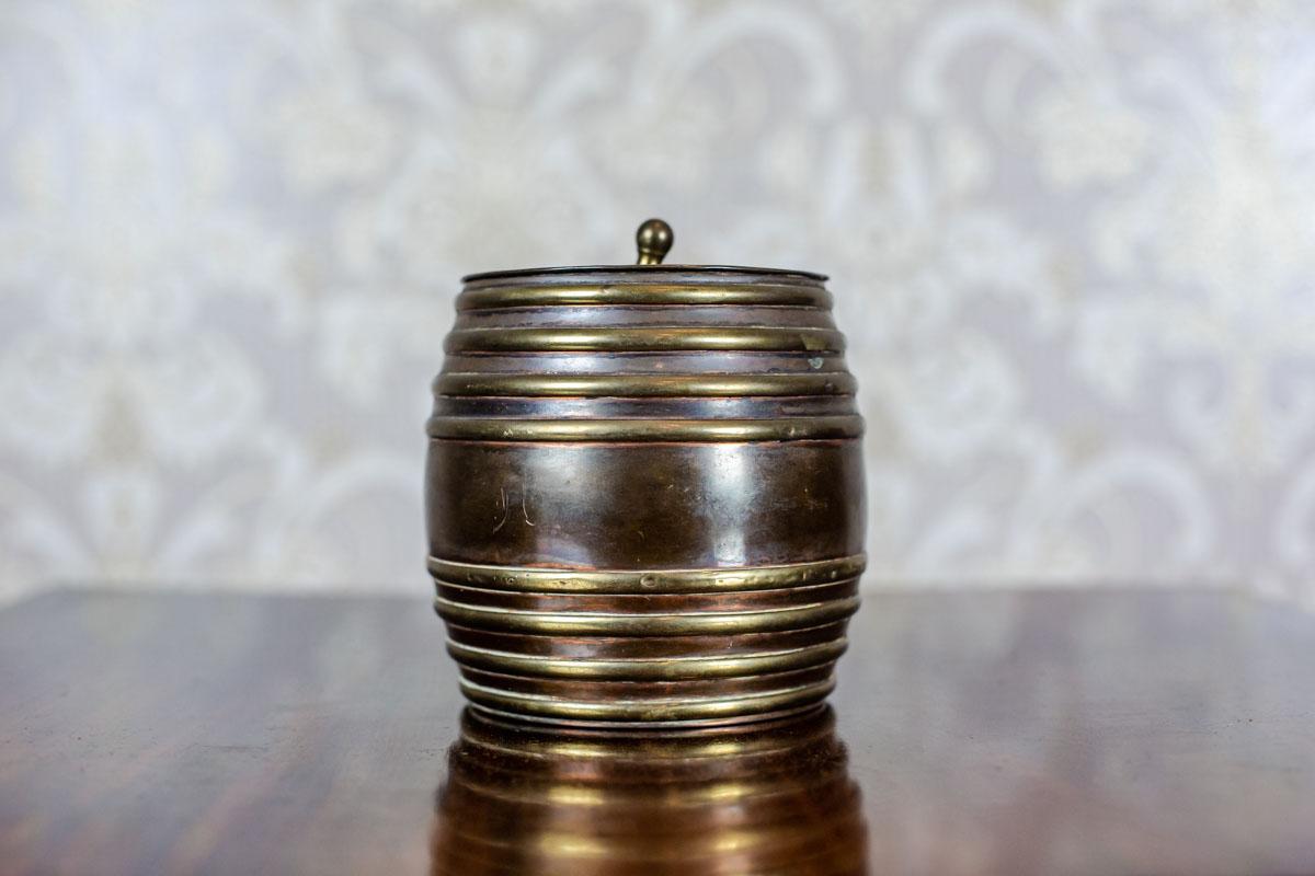 We present you a snuff box in the shape of a barrel with a lid.
The item is made of copper and brass.

This snuff box in good condition. The handle is distorted.
Moreover, there are dents on the brass embossed lines. The whole is covered in